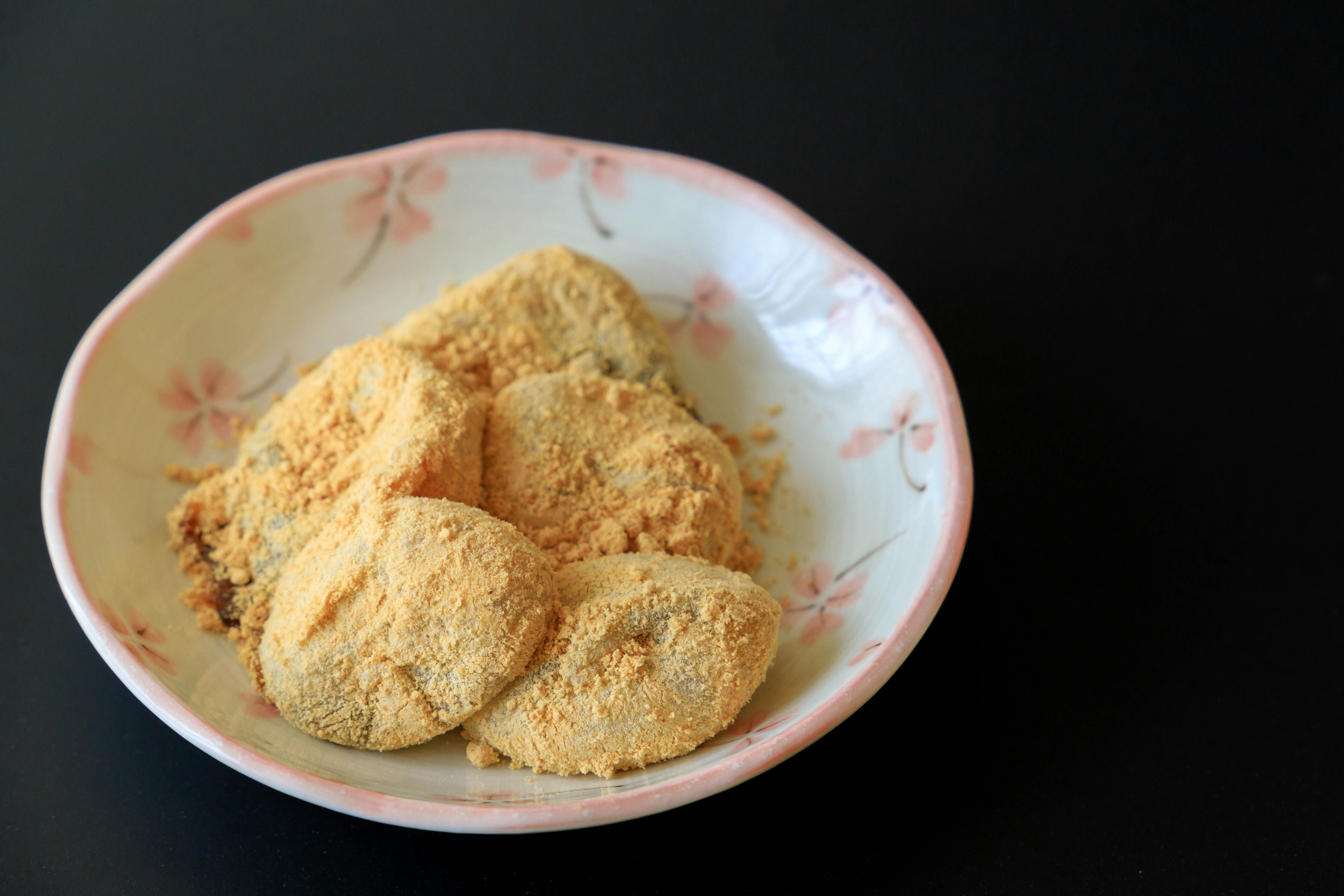 Dango covered in soybean flour on a floral plate