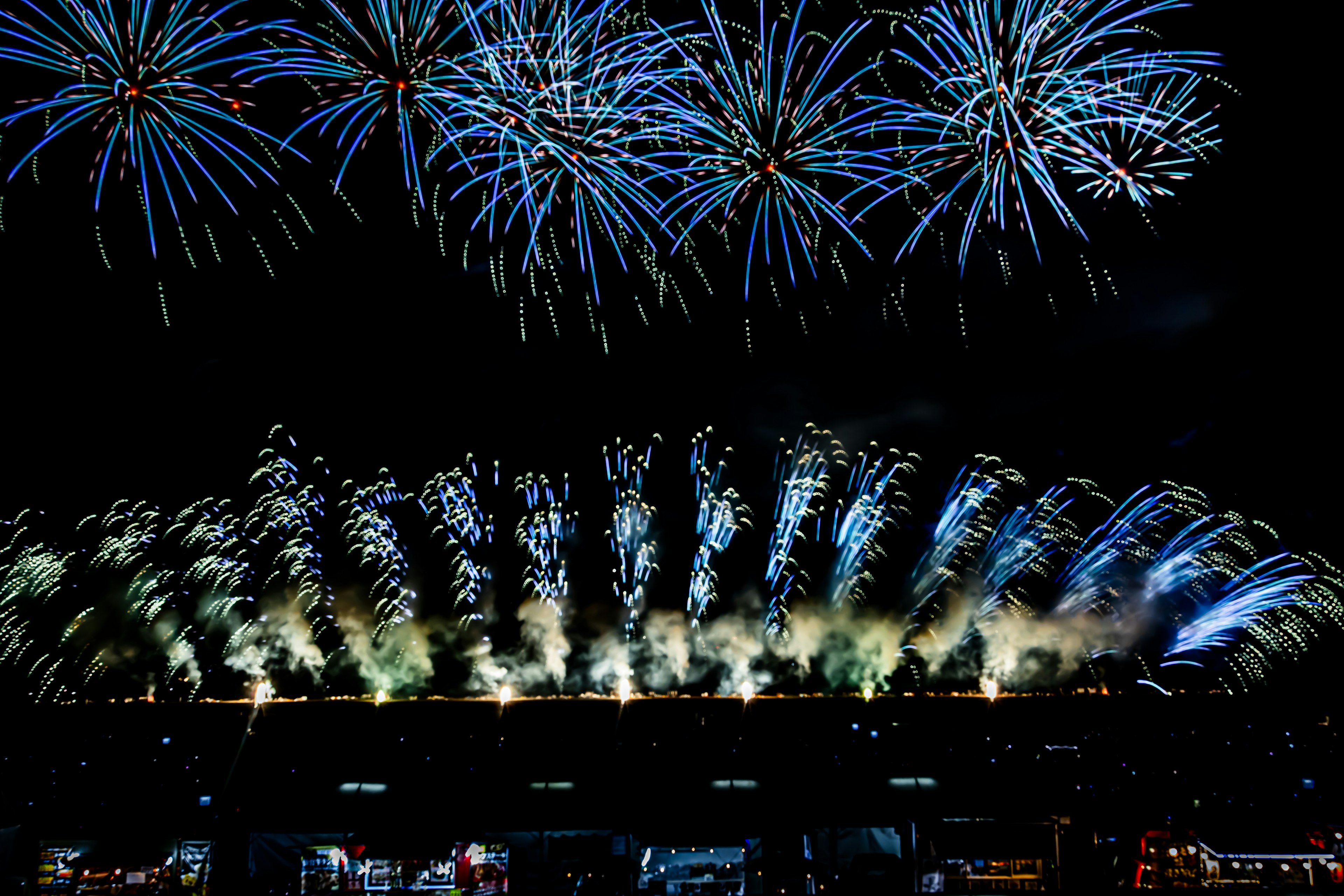 夜空に広がる青い花火と光の演出