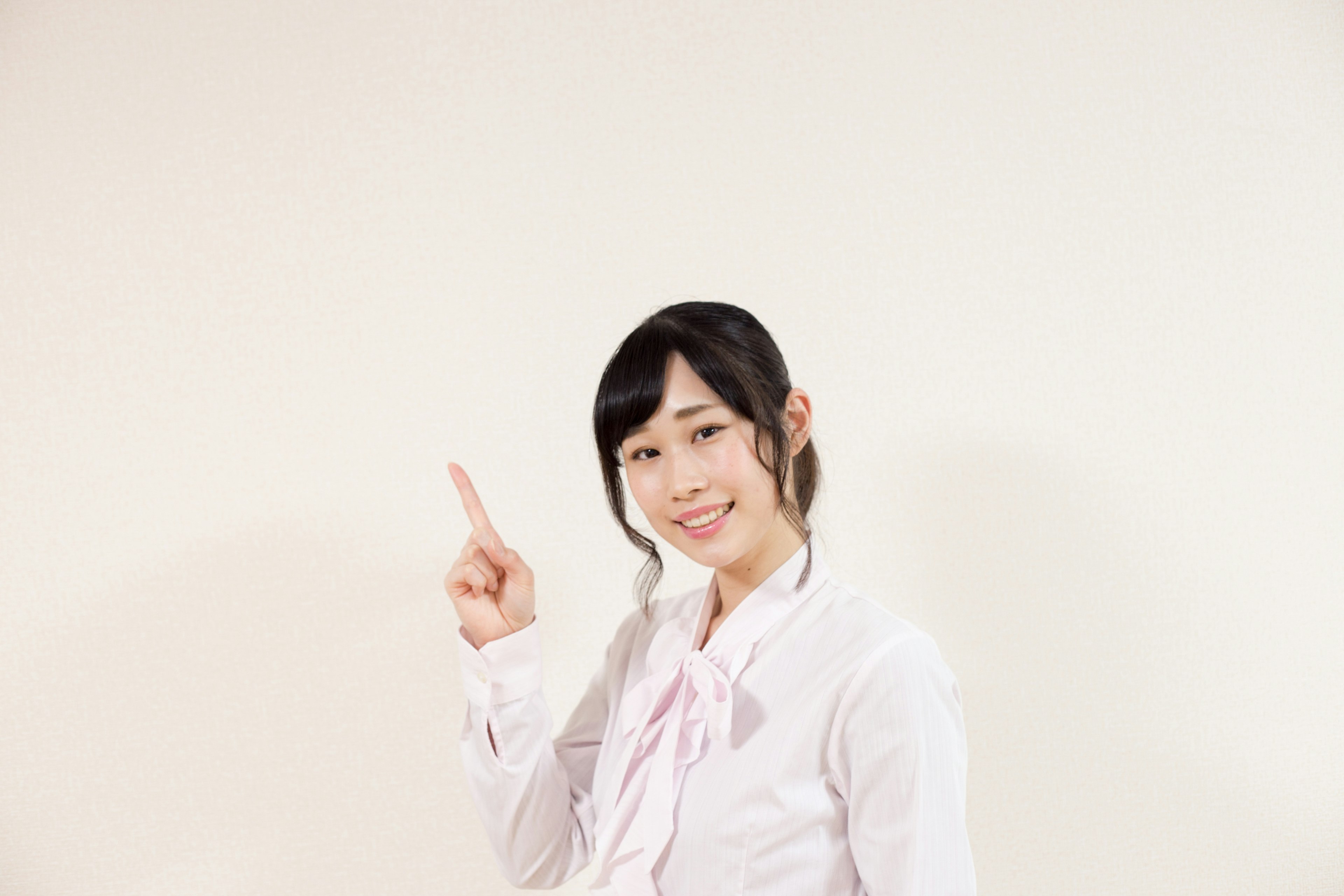 A woman in a white shirt is smiling and pointing upwards