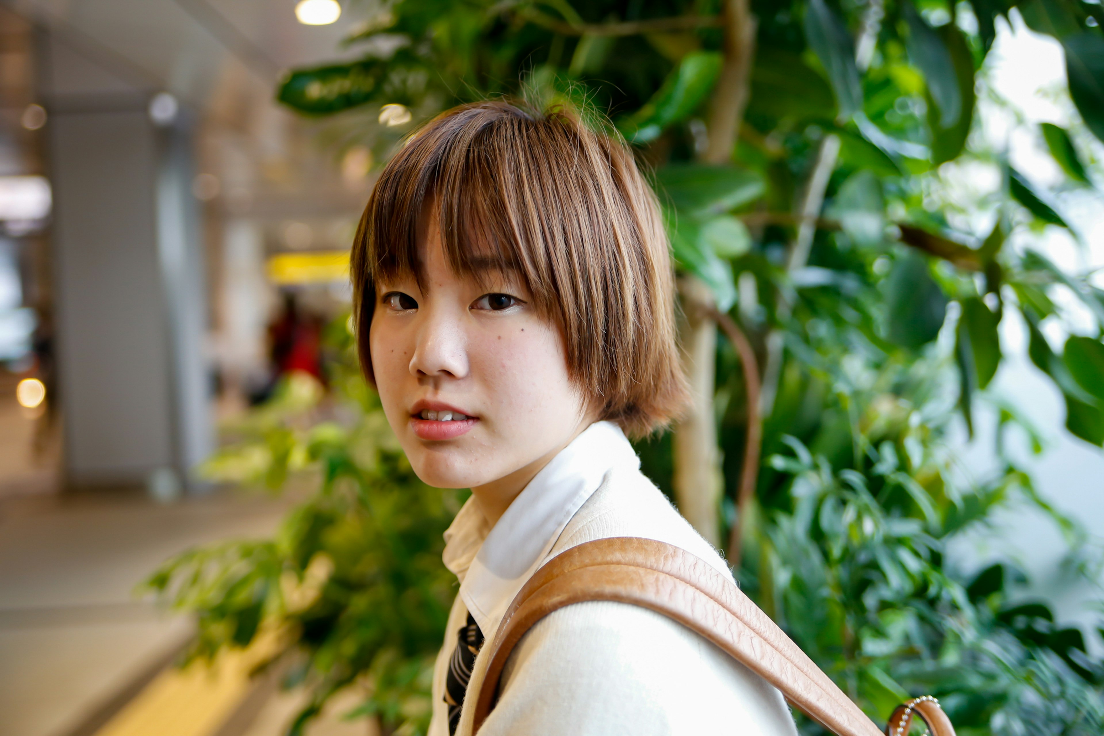 Jeune femme souriante devant des plantes vertes