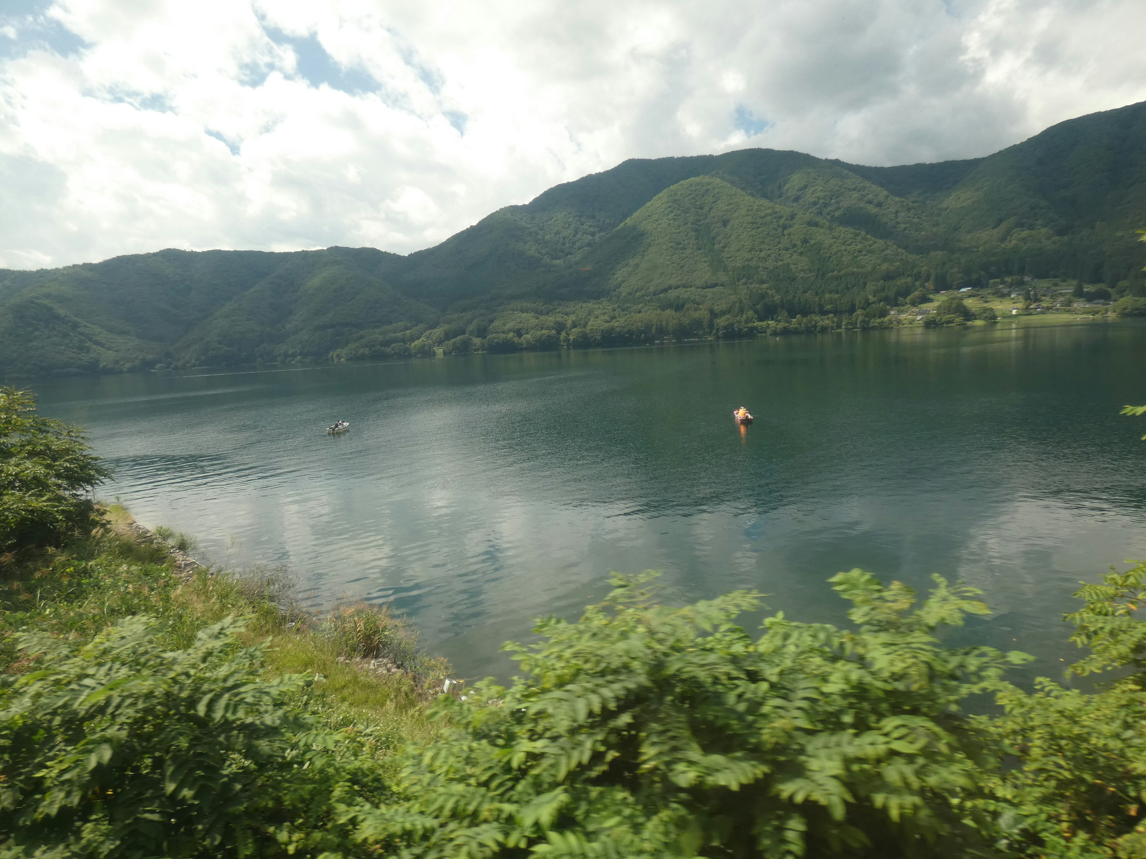 Lago tranquilo rodeado de montañas vegetación exuberante y superficie de agua calma