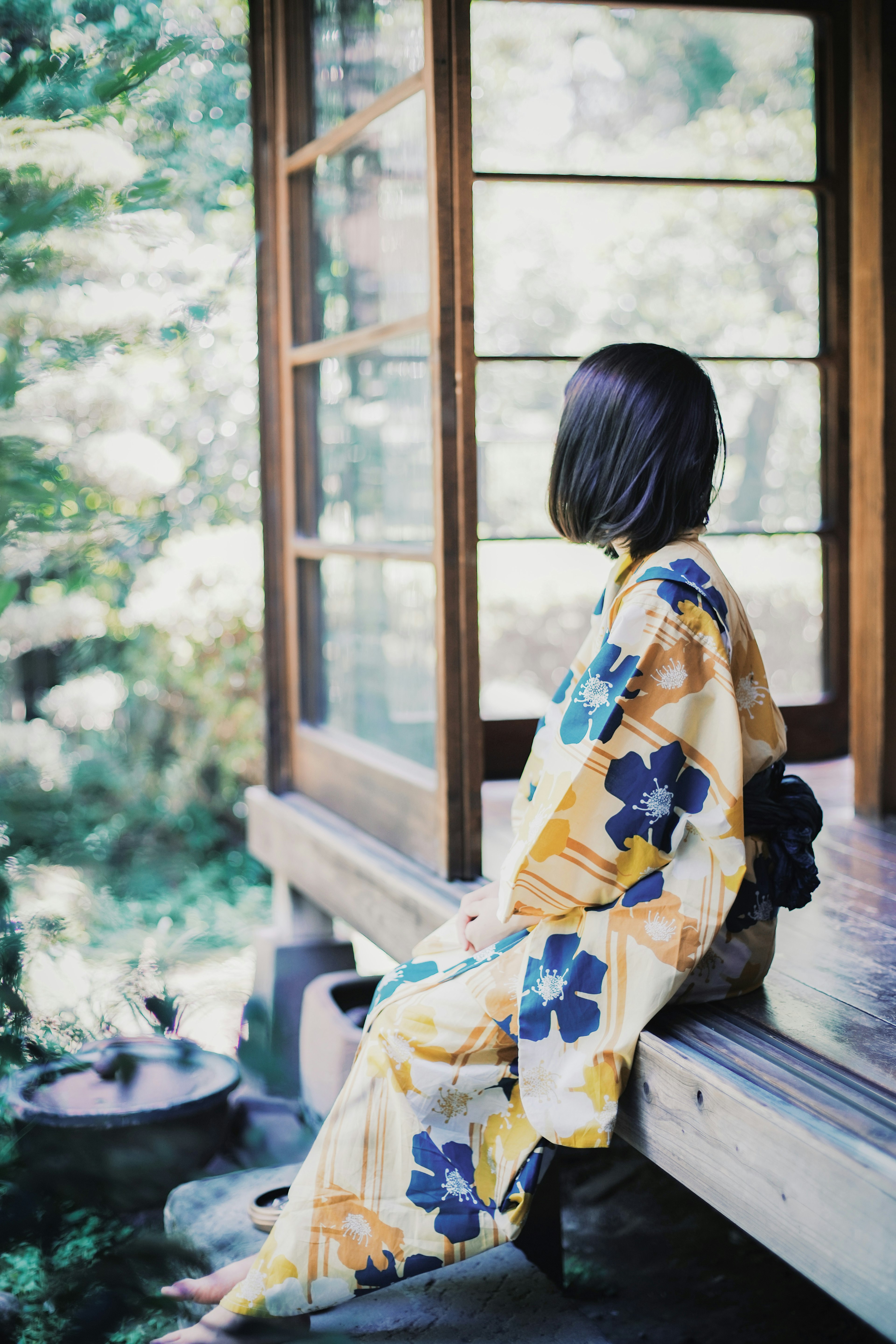 A woman in a kimono sitting outside a wooden house