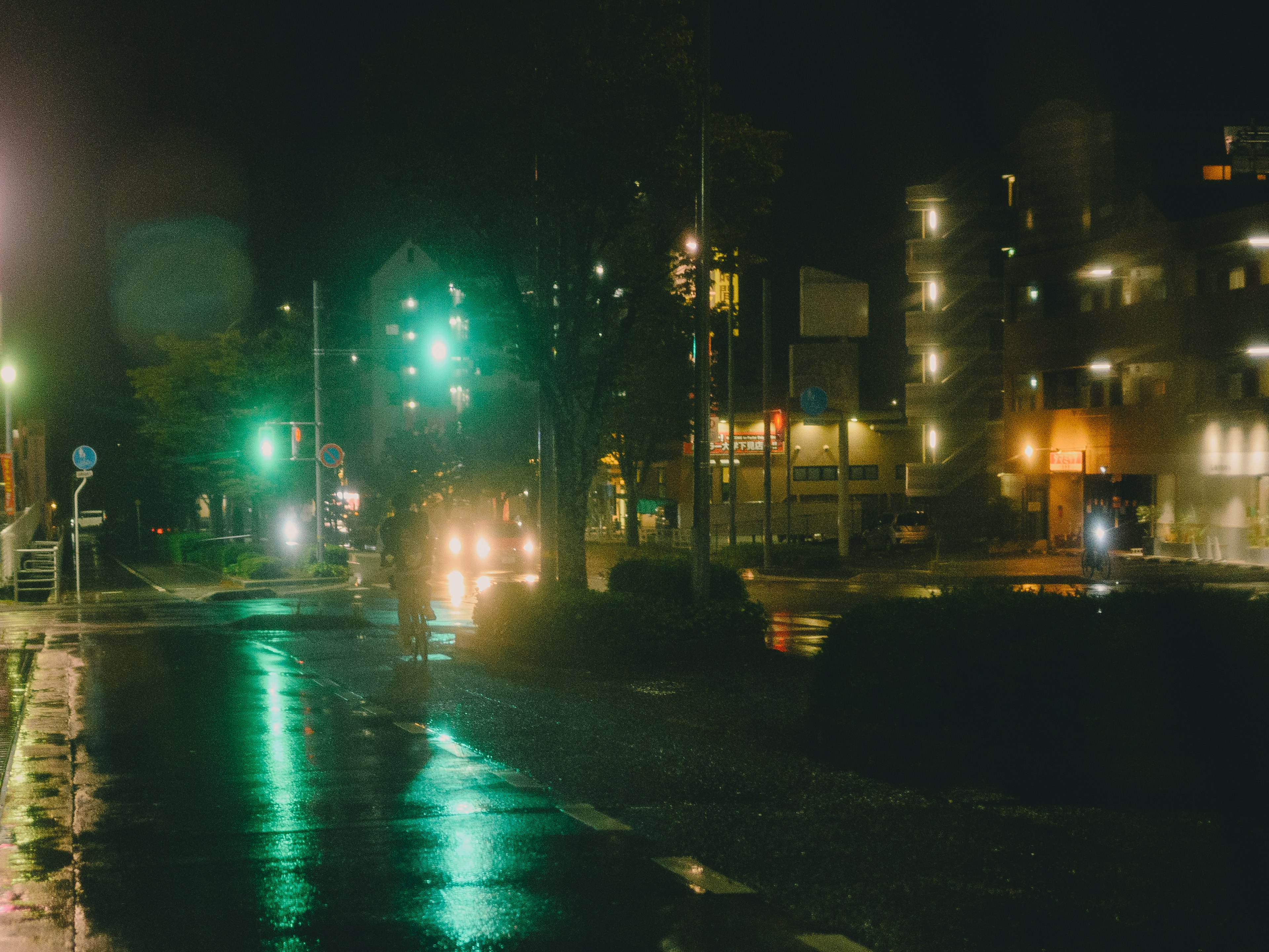 夜間城市交叉口，綠色交通燈和濕滑的道路