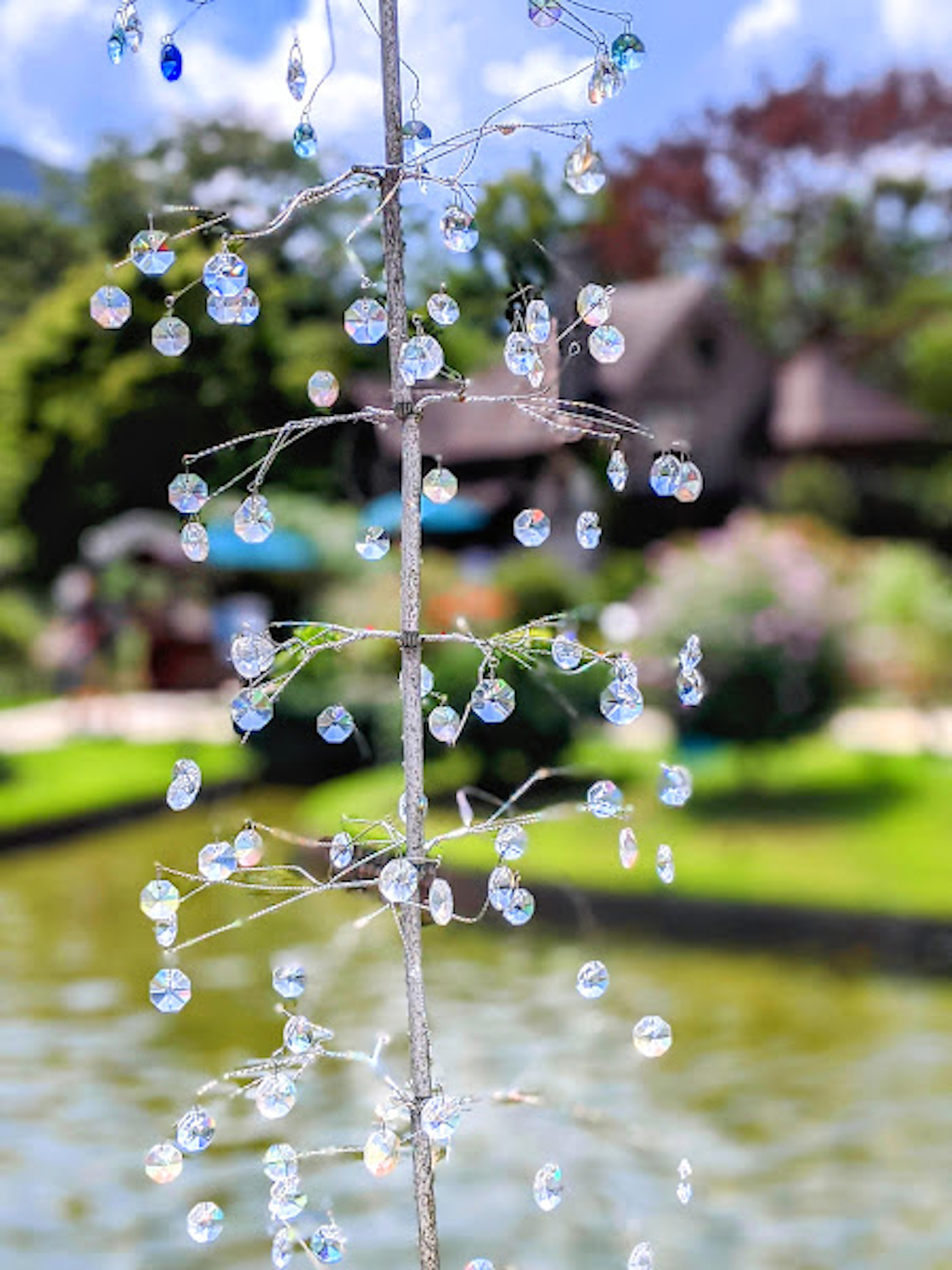 Crystal decorations shimmering near a tranquil water feature in a garden