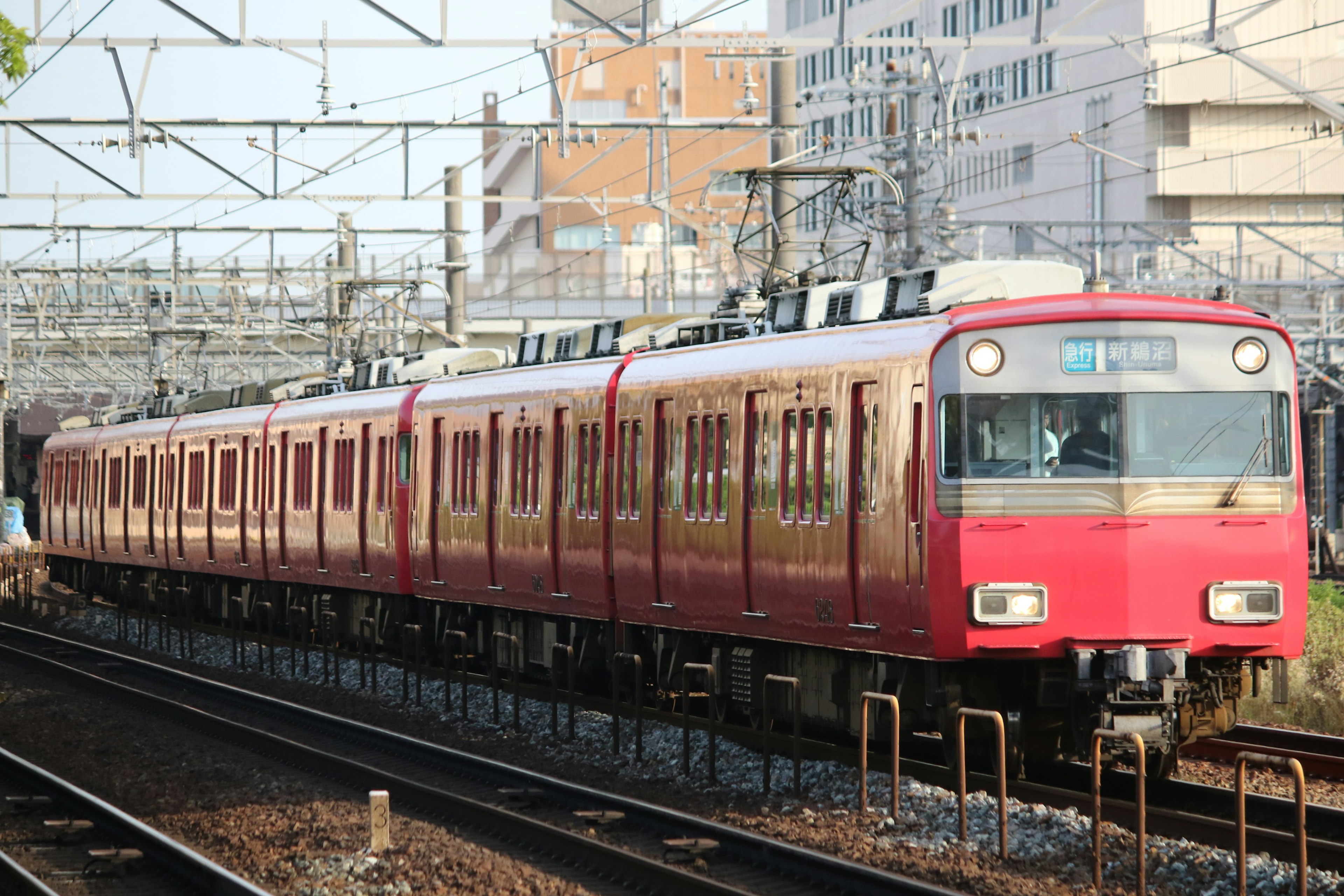 Red train running on tracks with urban background