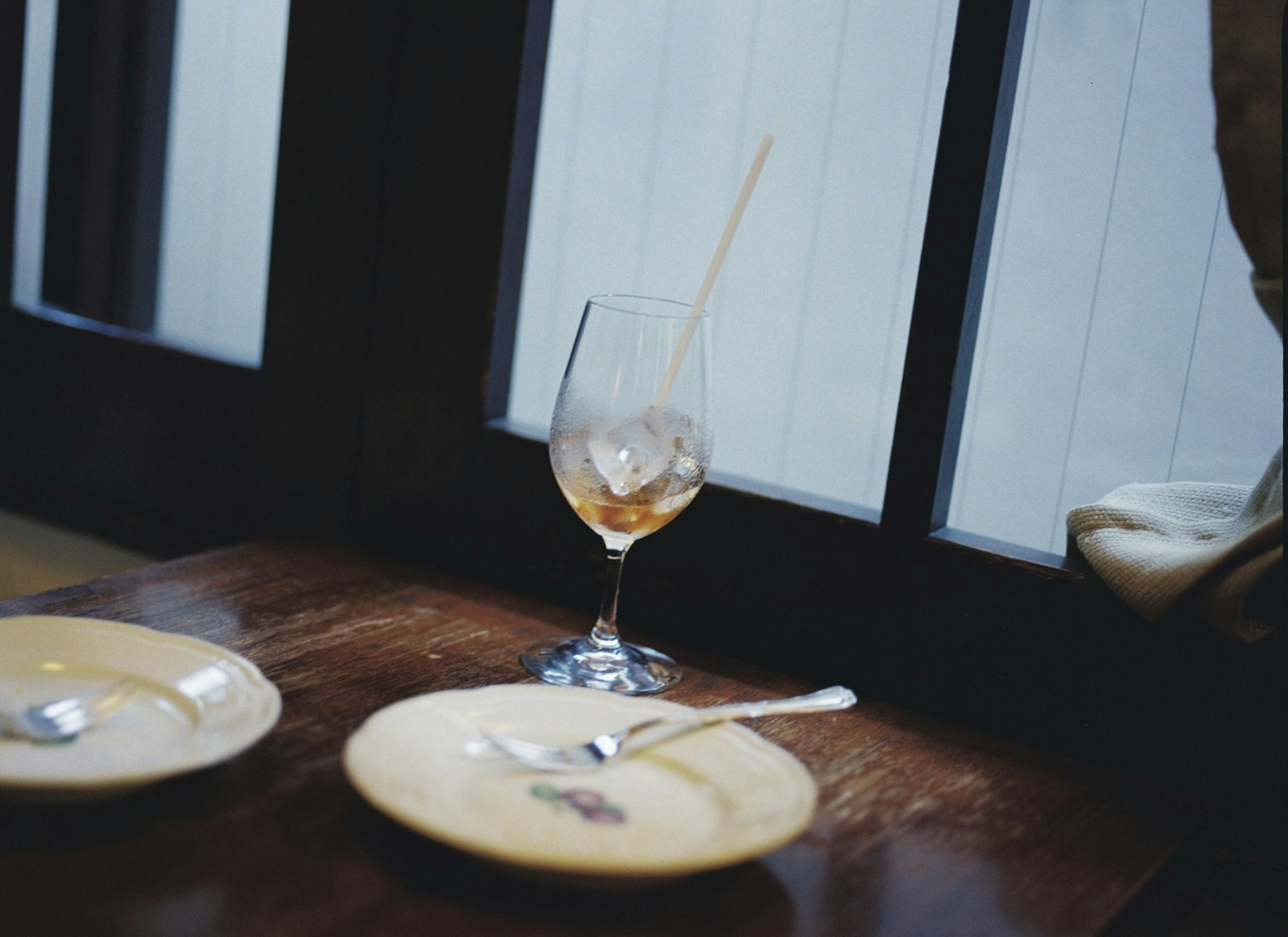 Wine glass with ice on a wooden table next to two plates