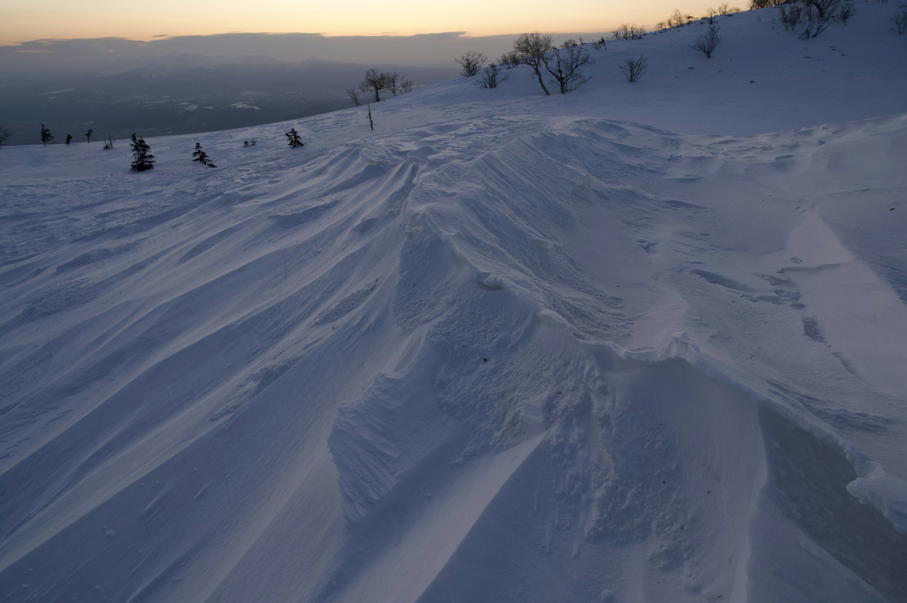 雪に覆われた丘陵の美しい景色 日没時の柔らかい光と滑らかな雪の模様