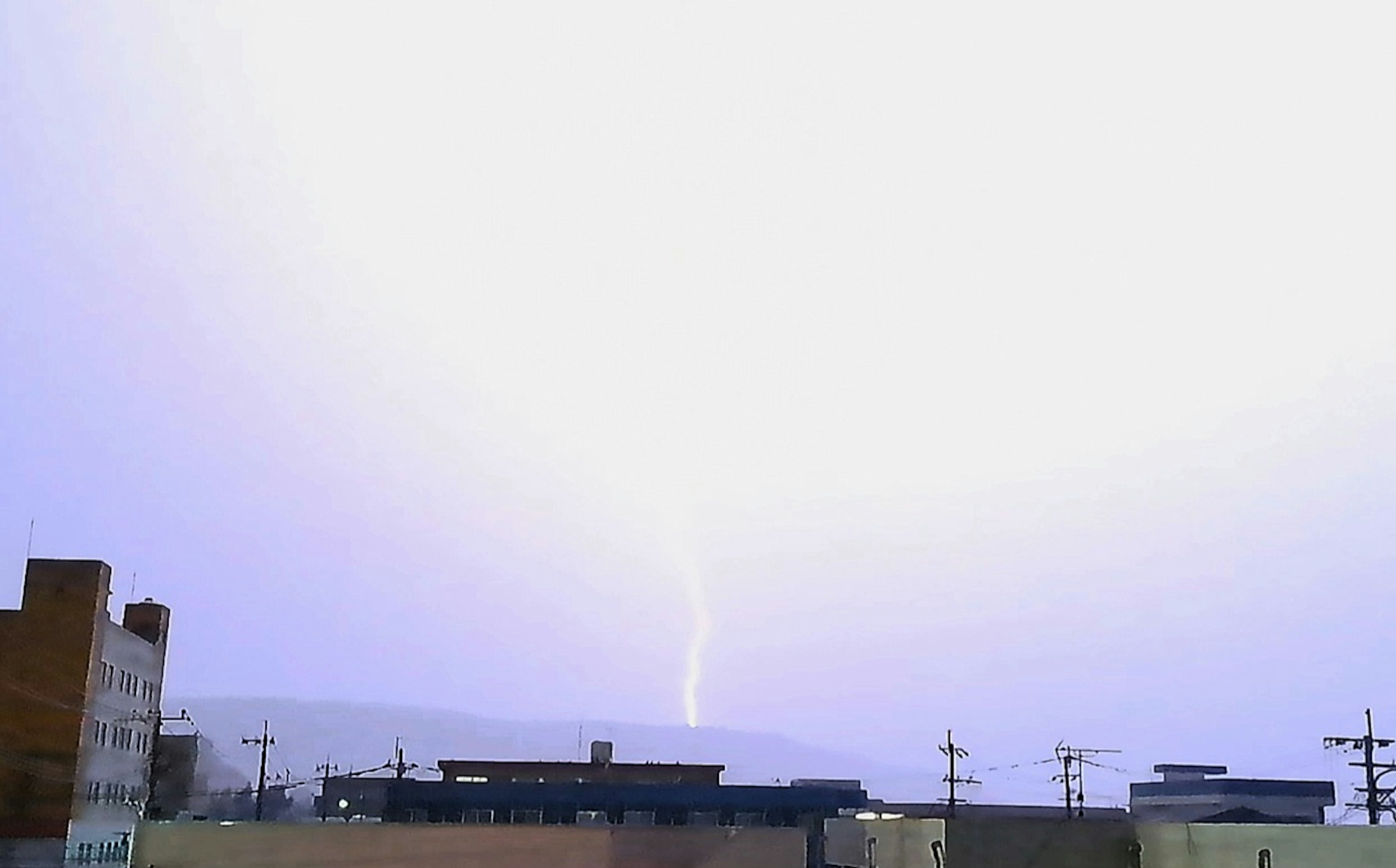 Lightning striking in a cloudy sky over buildings