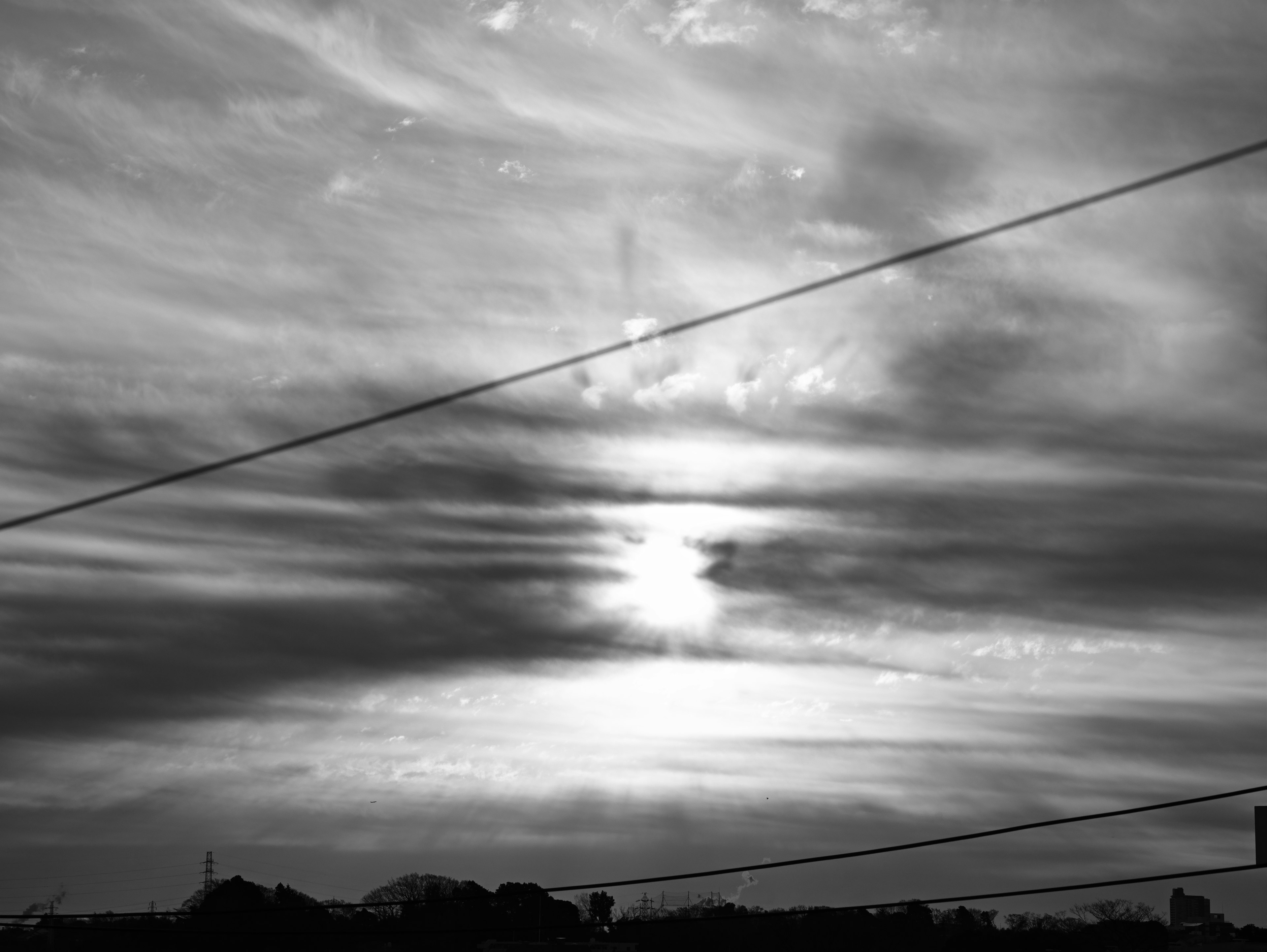 黒と白の空に広がる雲と太陽の光