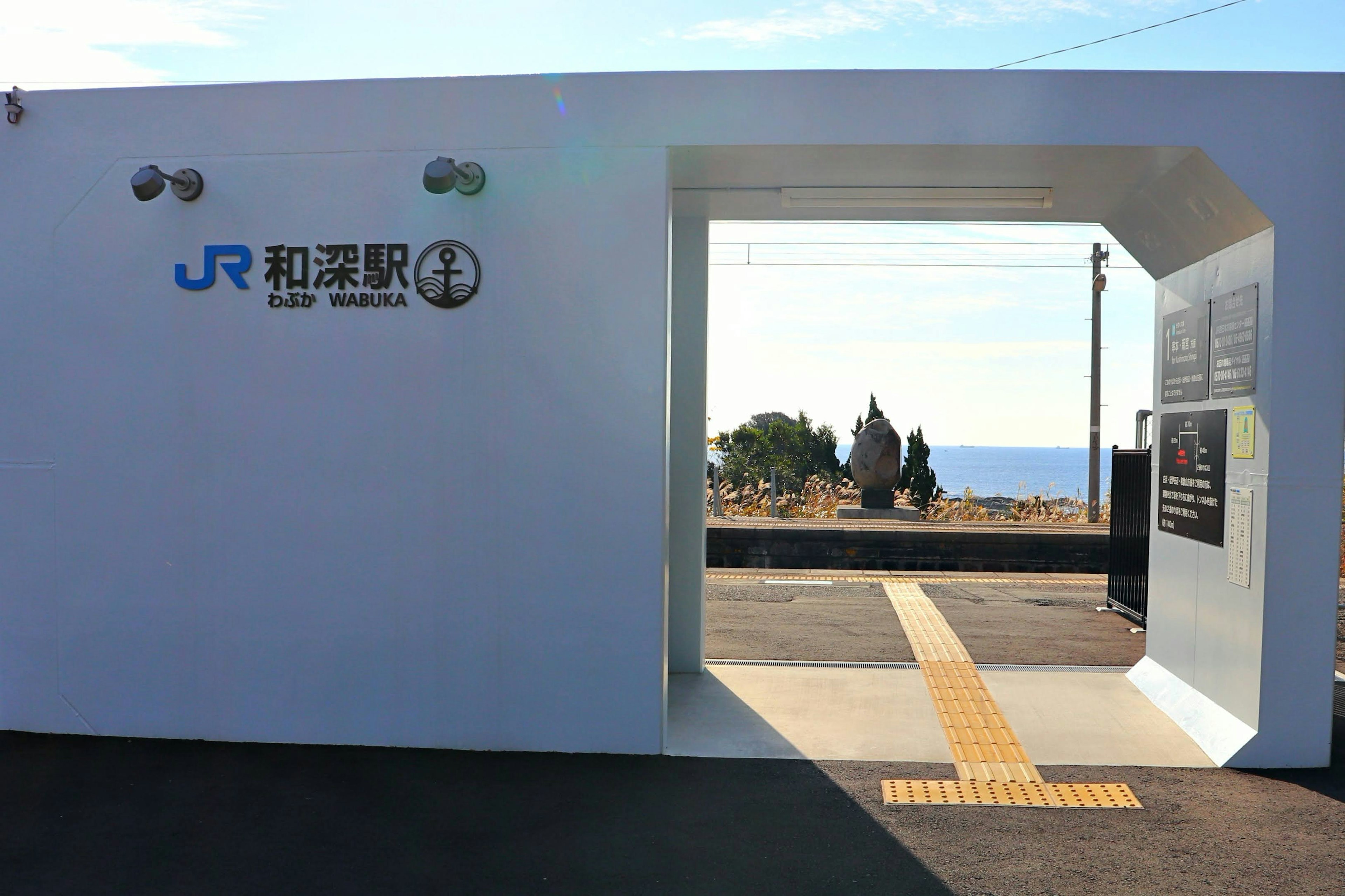 Pintu Stasiun JR Wakayama dengan dinding putih dan pemandangan laut