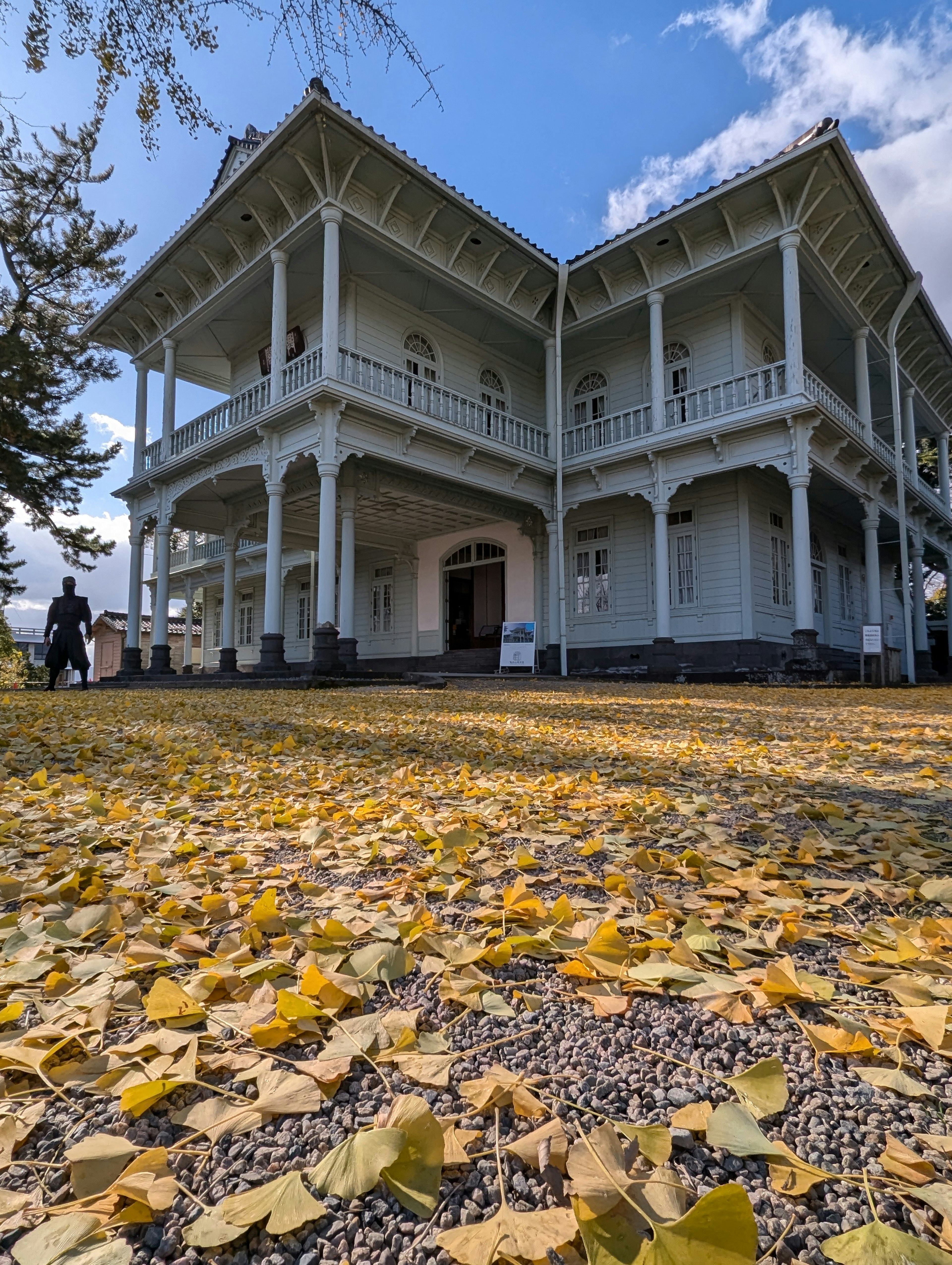 Edificio blanco rodeado de hojas de otoño y cielo azul