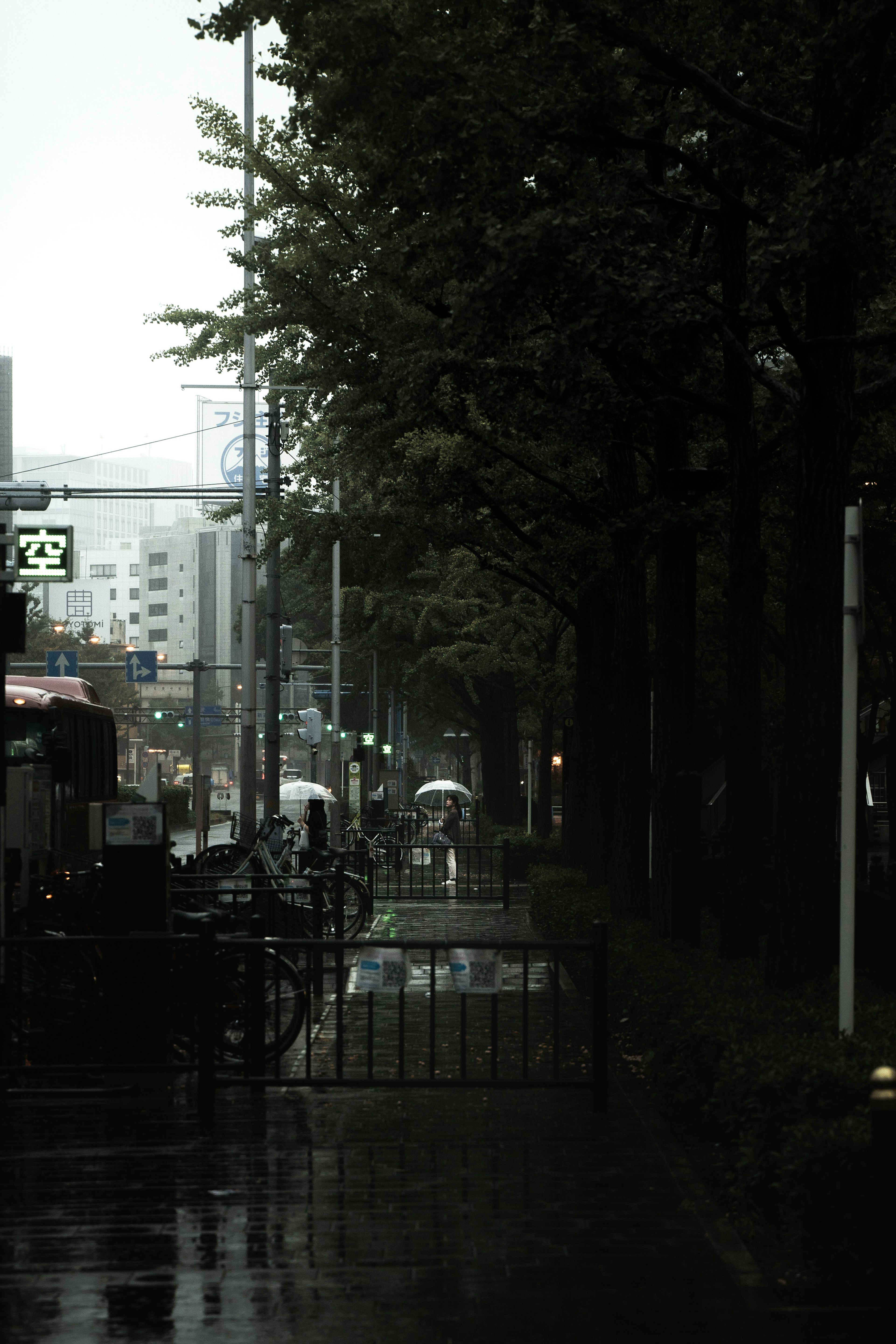 ทิวทัศน์เมืองในสายฝนมีจักรยานและคนที่ถือร่ม