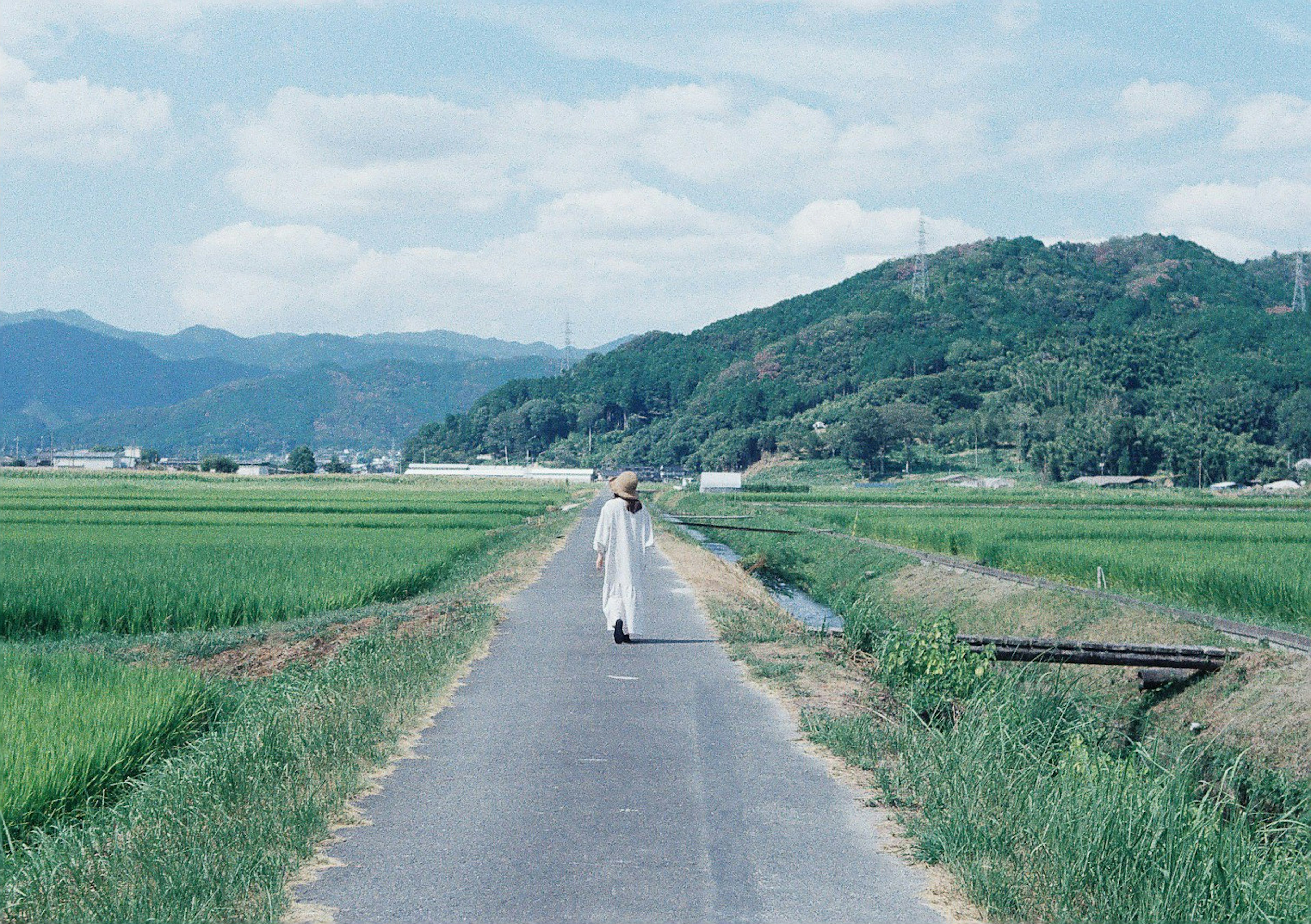 Eine Person, die auf einem Landweg unter einem blauen Himmel geht