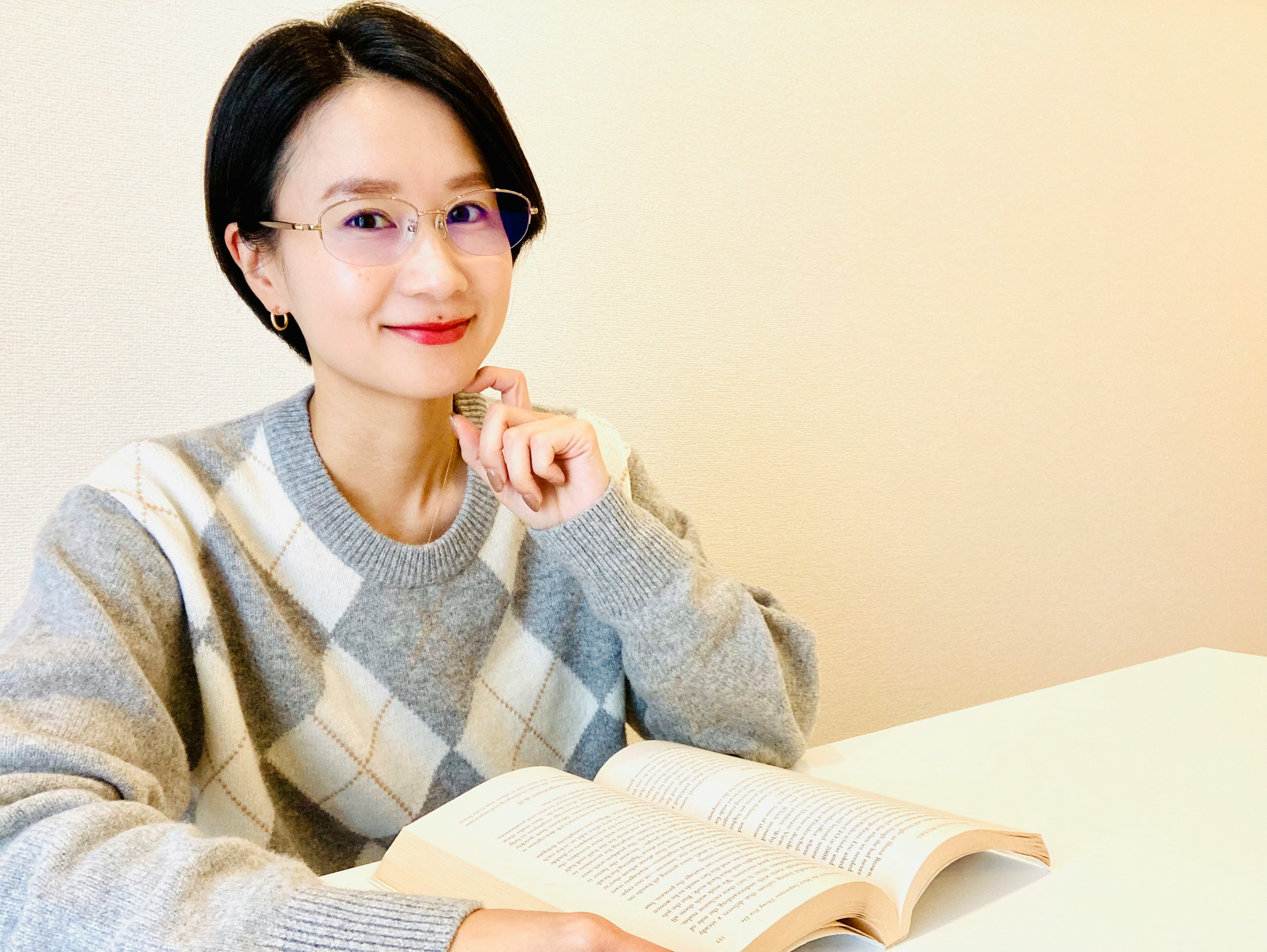 Una mujer sonriente leyendo un libro con gafas en un ambiente acogedor