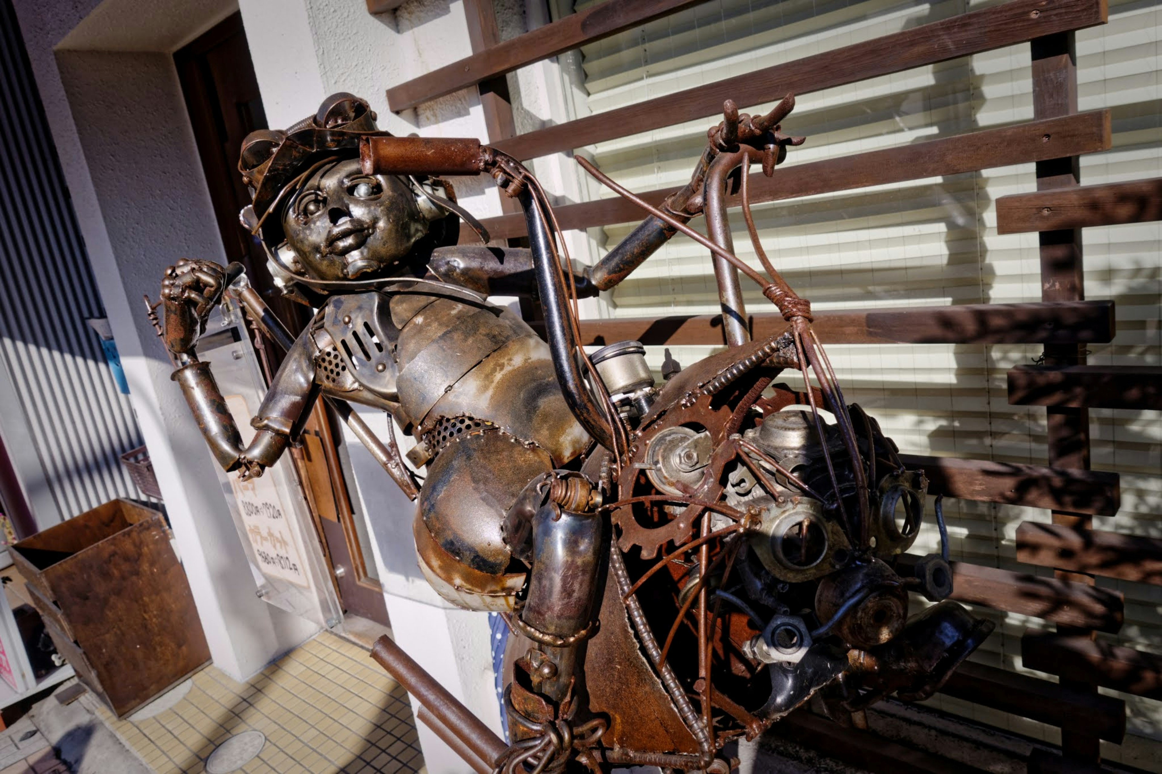 Escultura de metal de una figura humanoide exhibida frente a una ventana