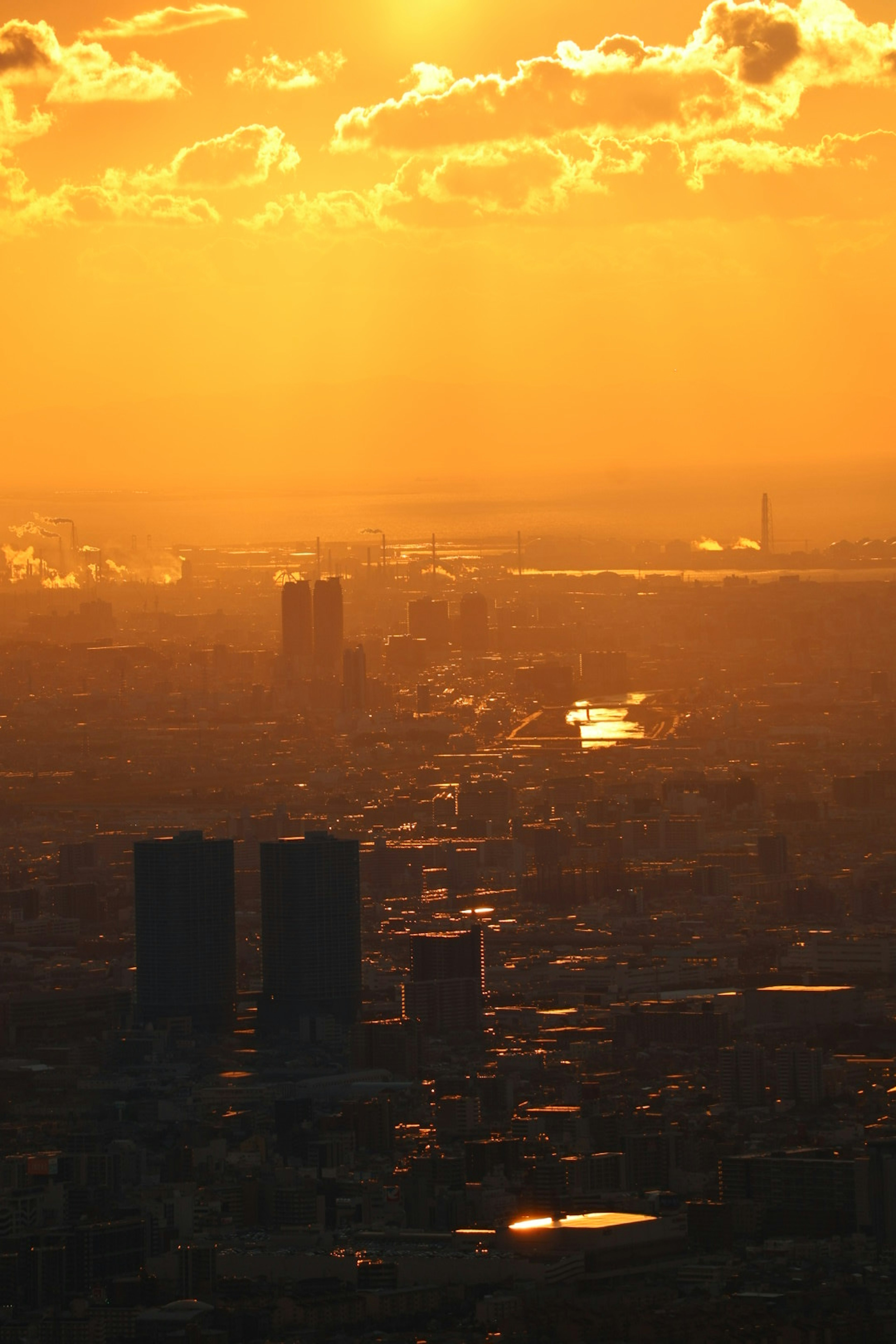 オレンジ色の夕焼けに包まれた都市の風景 高層ビルと川が見える