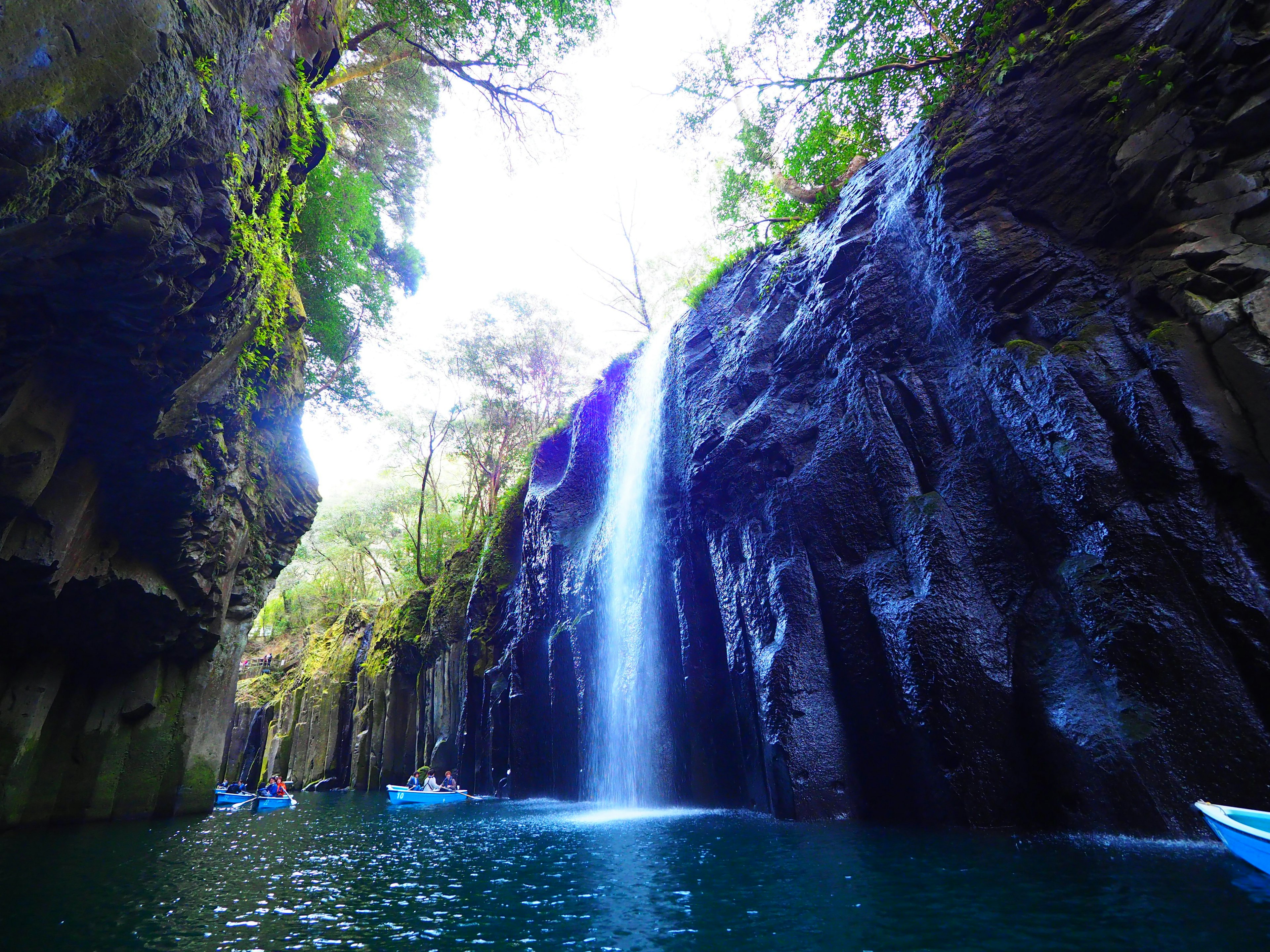 Vue panoramique d'un canyon verdoyant avec une cascade et un lac bleu