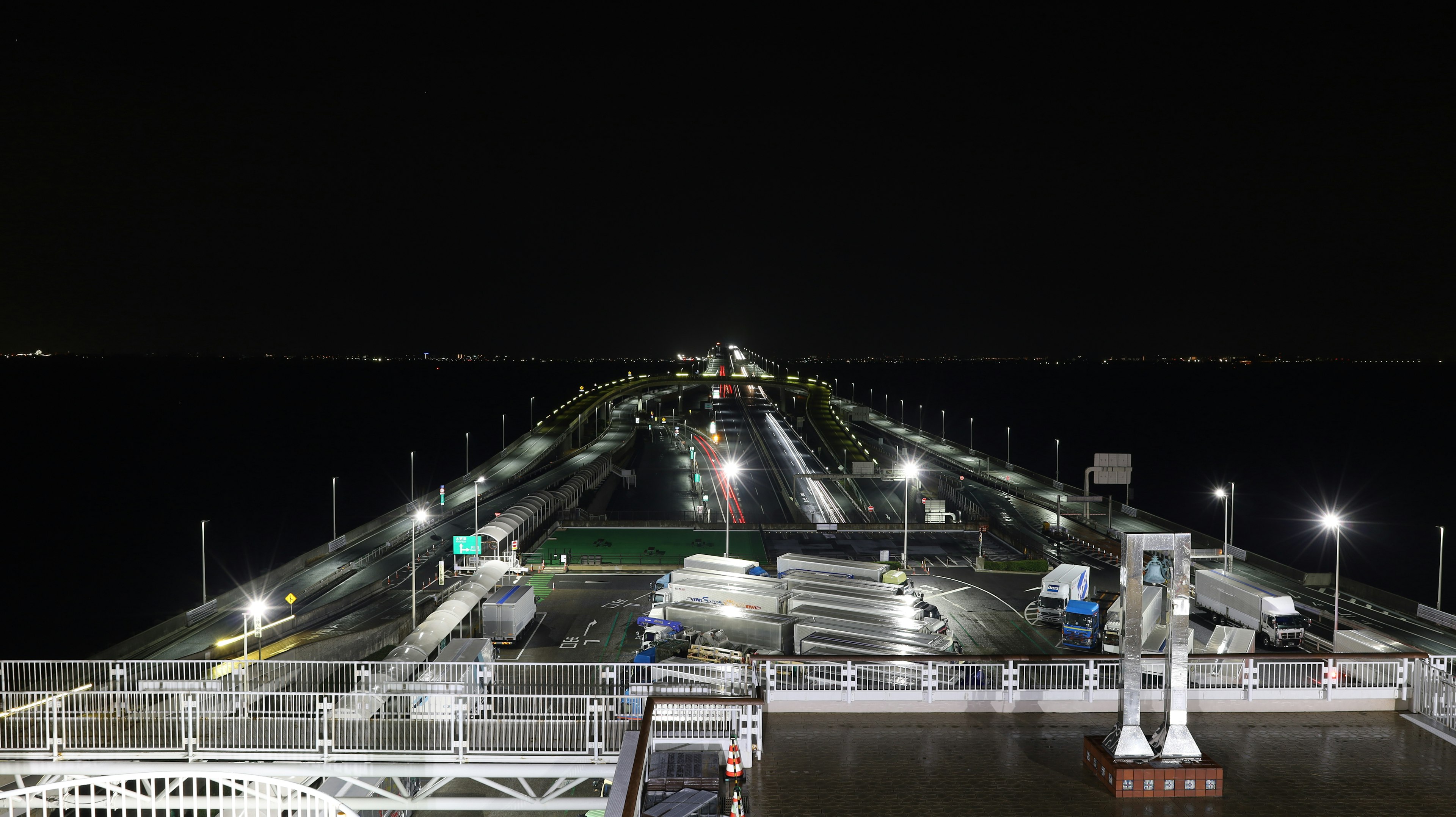 Pemandangan malam dermaga dengan jalur yang diterangi dan laut