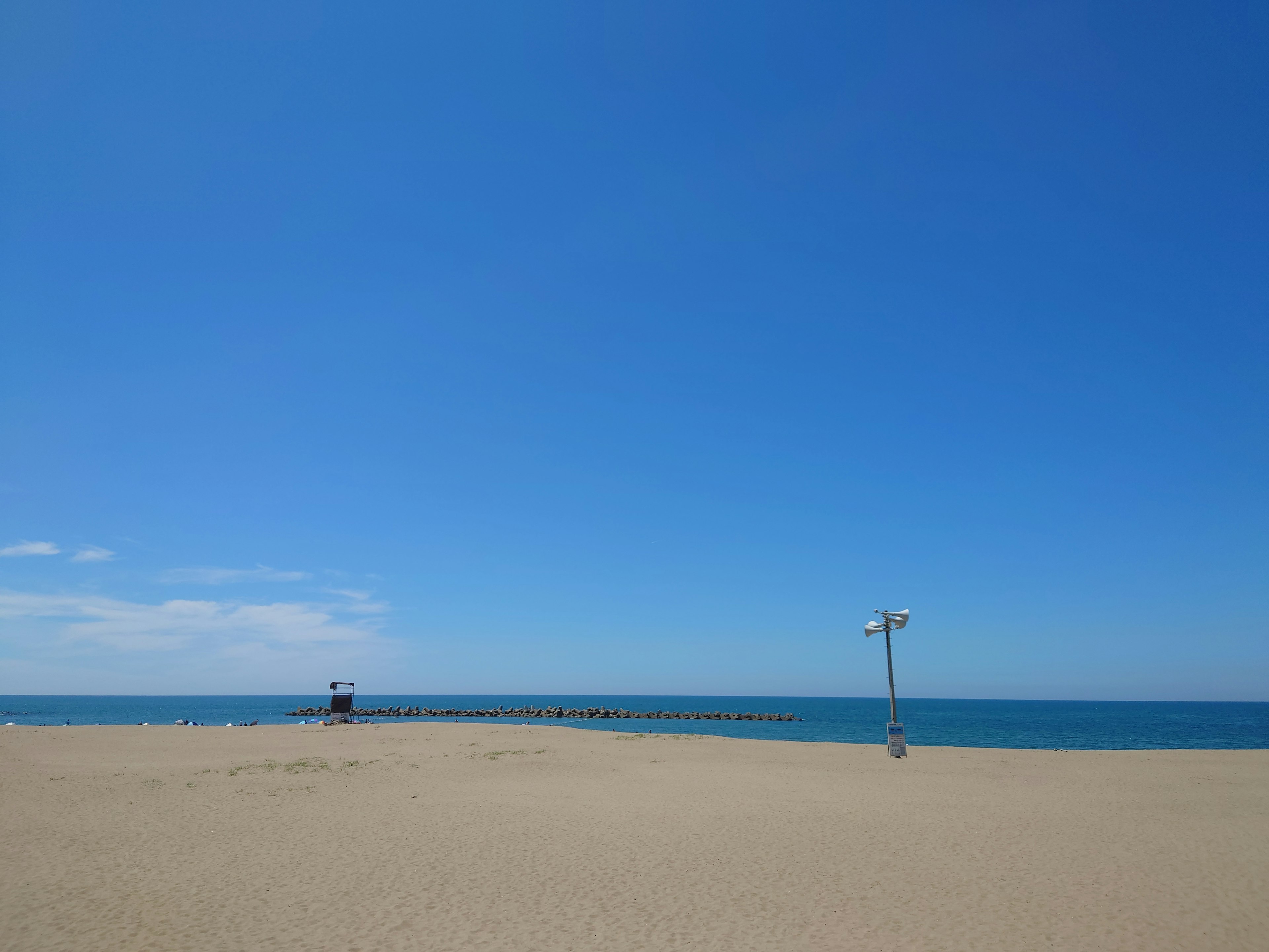 海灘場景，晴朗的藍天和海洋，沙灘和遠處的燈塔