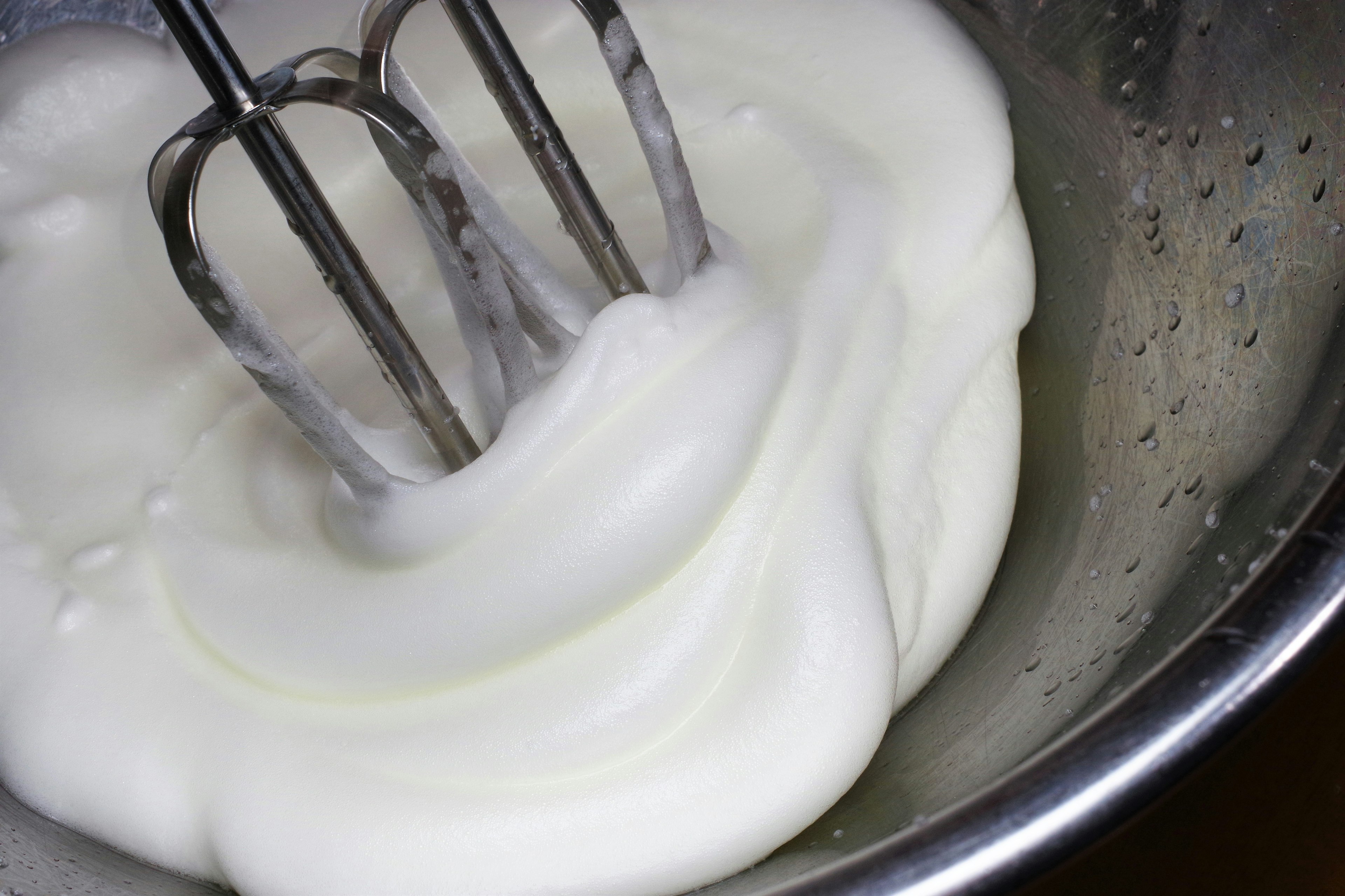 Bowl of whipped cream mixed with a hand mixer