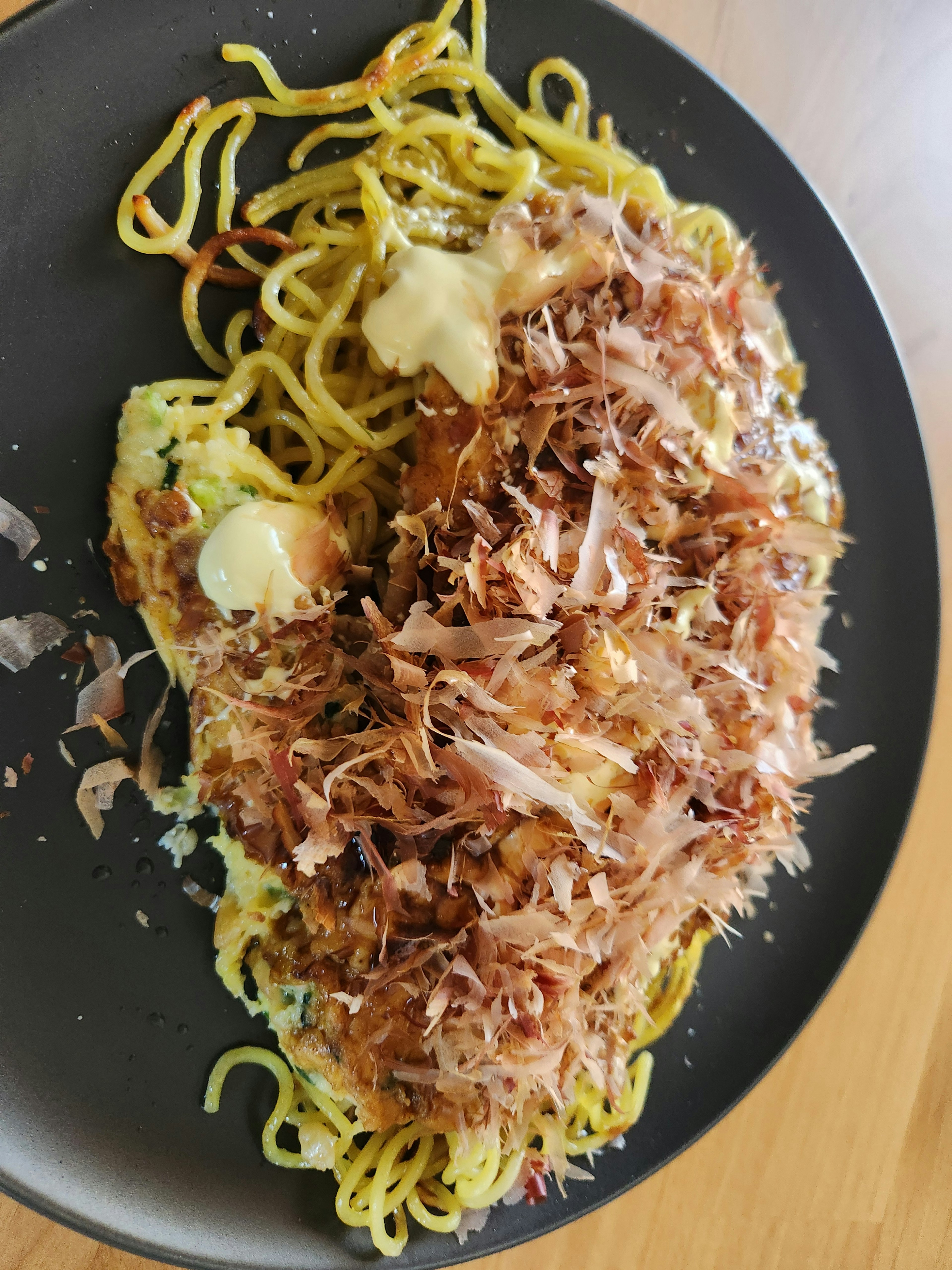 Dish featuring yakisoba topped with okonomiyaki and bonito flakes