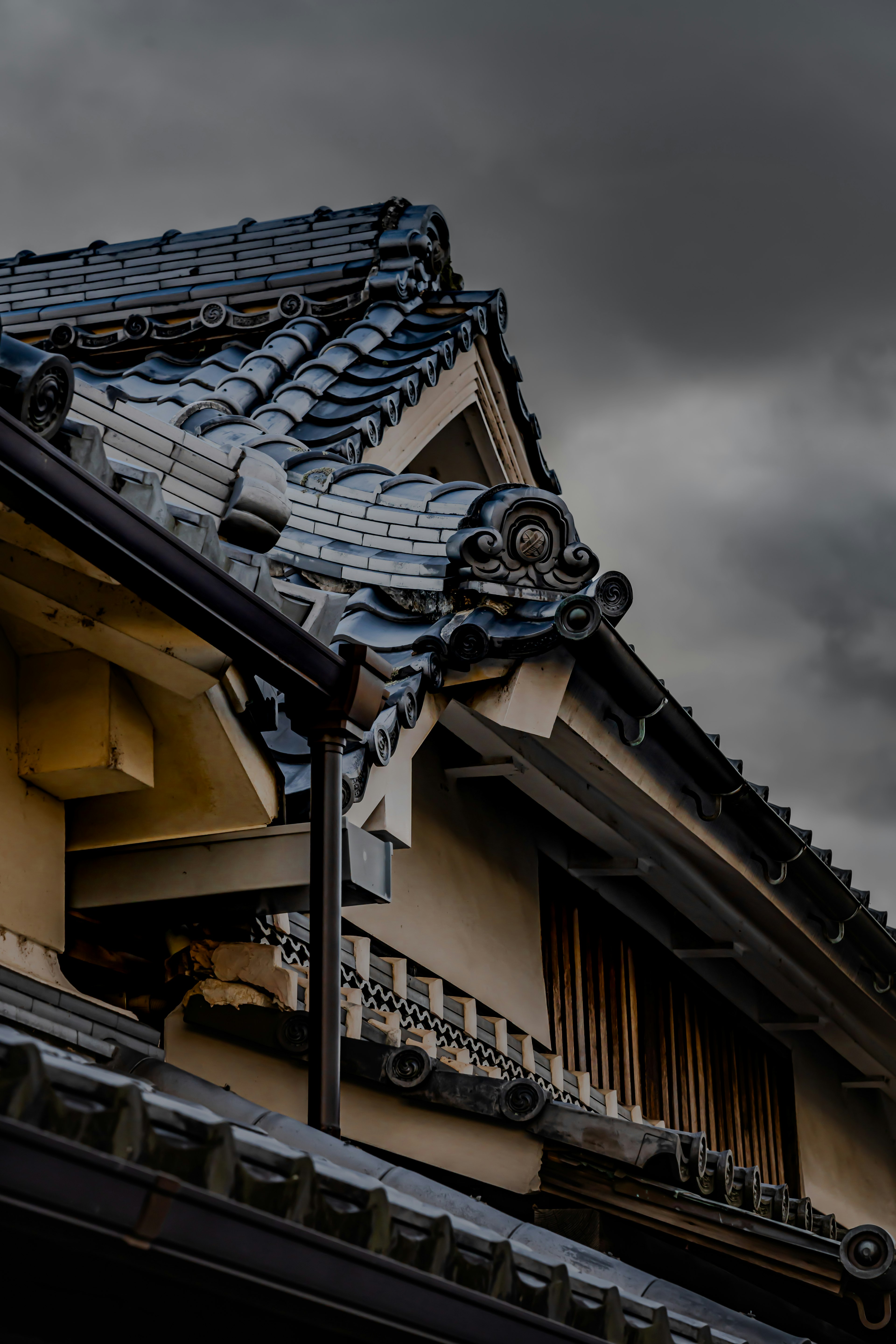 Toit en tuiles japonais traditionnel avec des détails complexes sous un ciel sombre