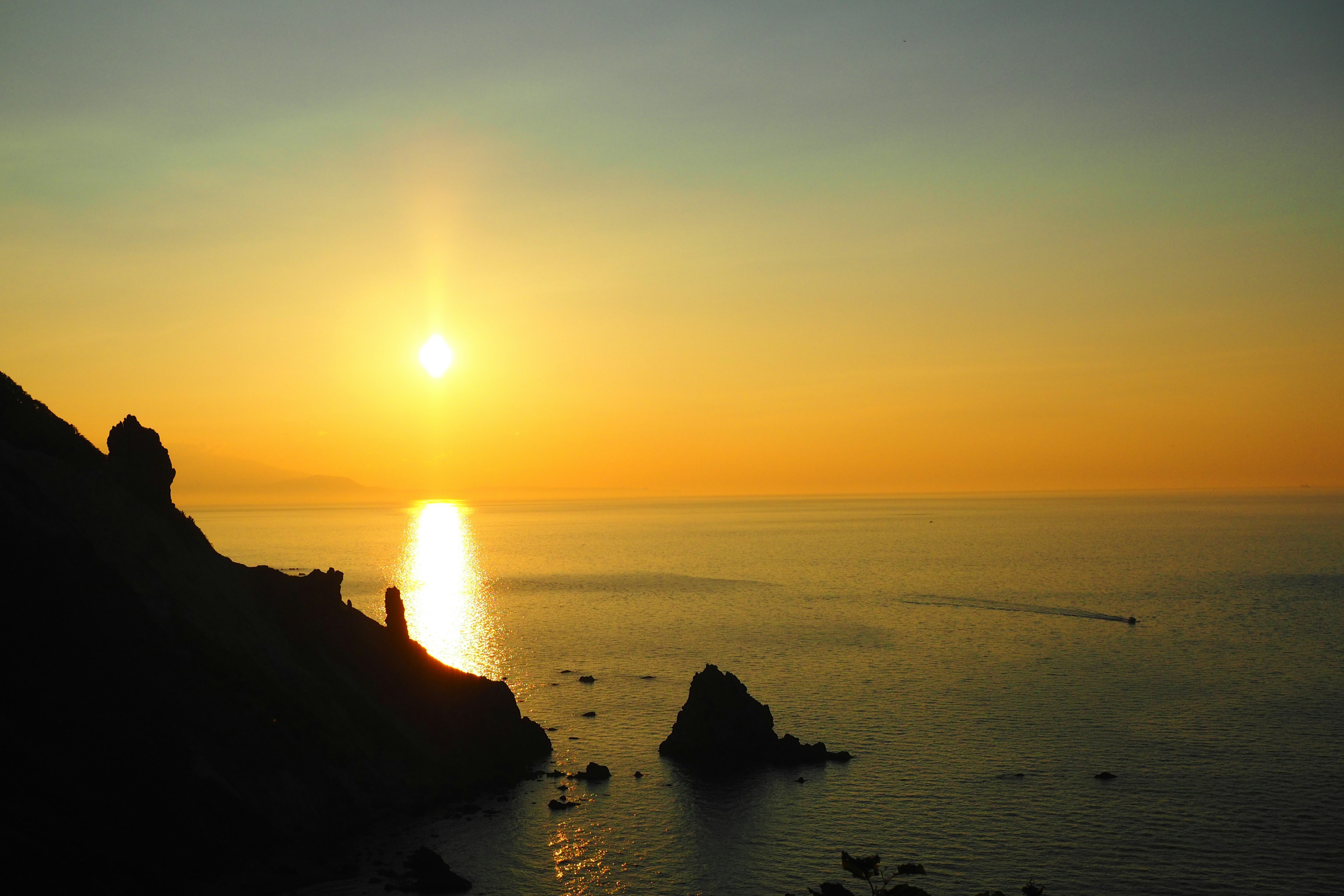 Escena costera al atardecer con aguas tranquilas y formaciones rocosas