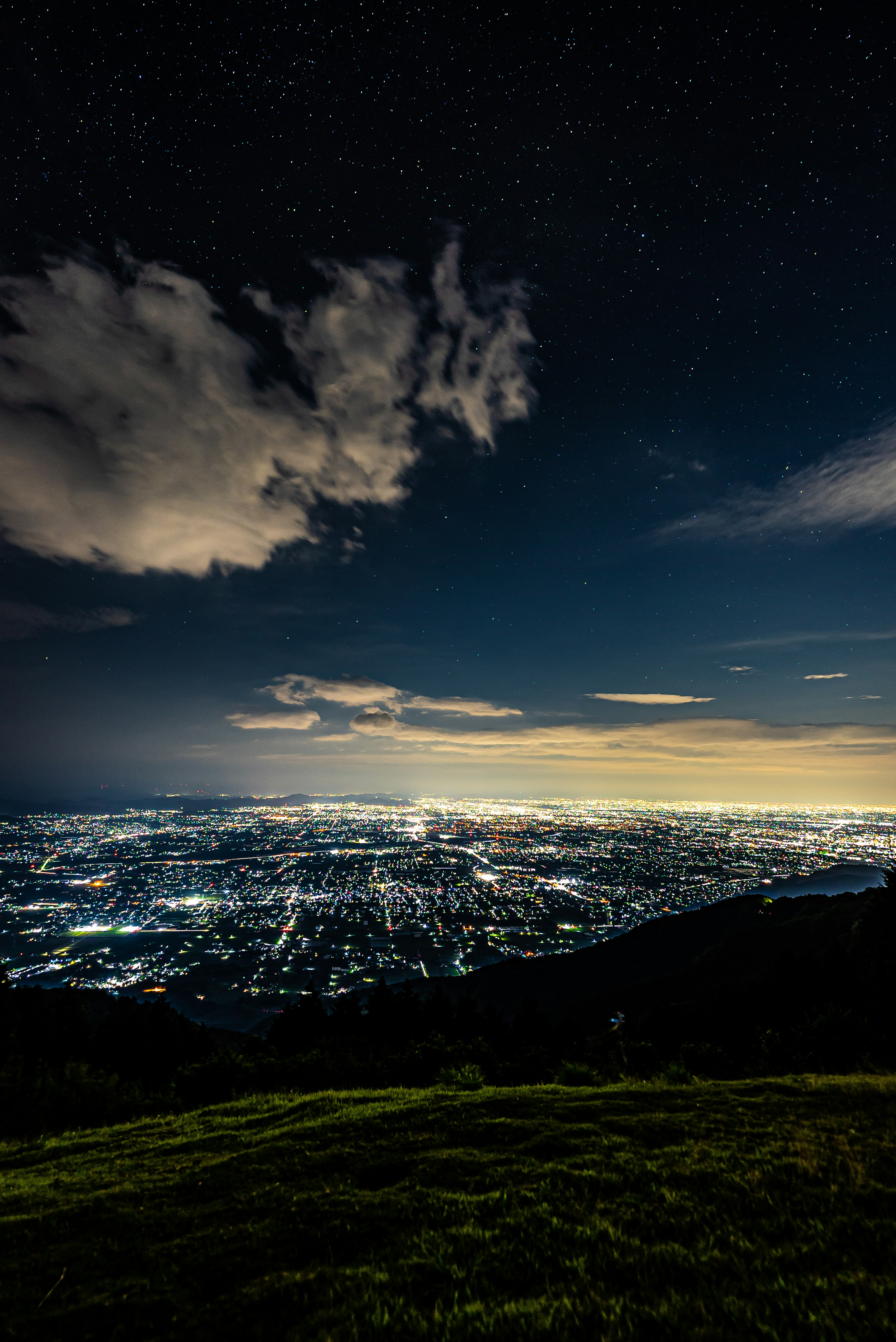 夜空に輝く星々と都市の明かりが広がる風景