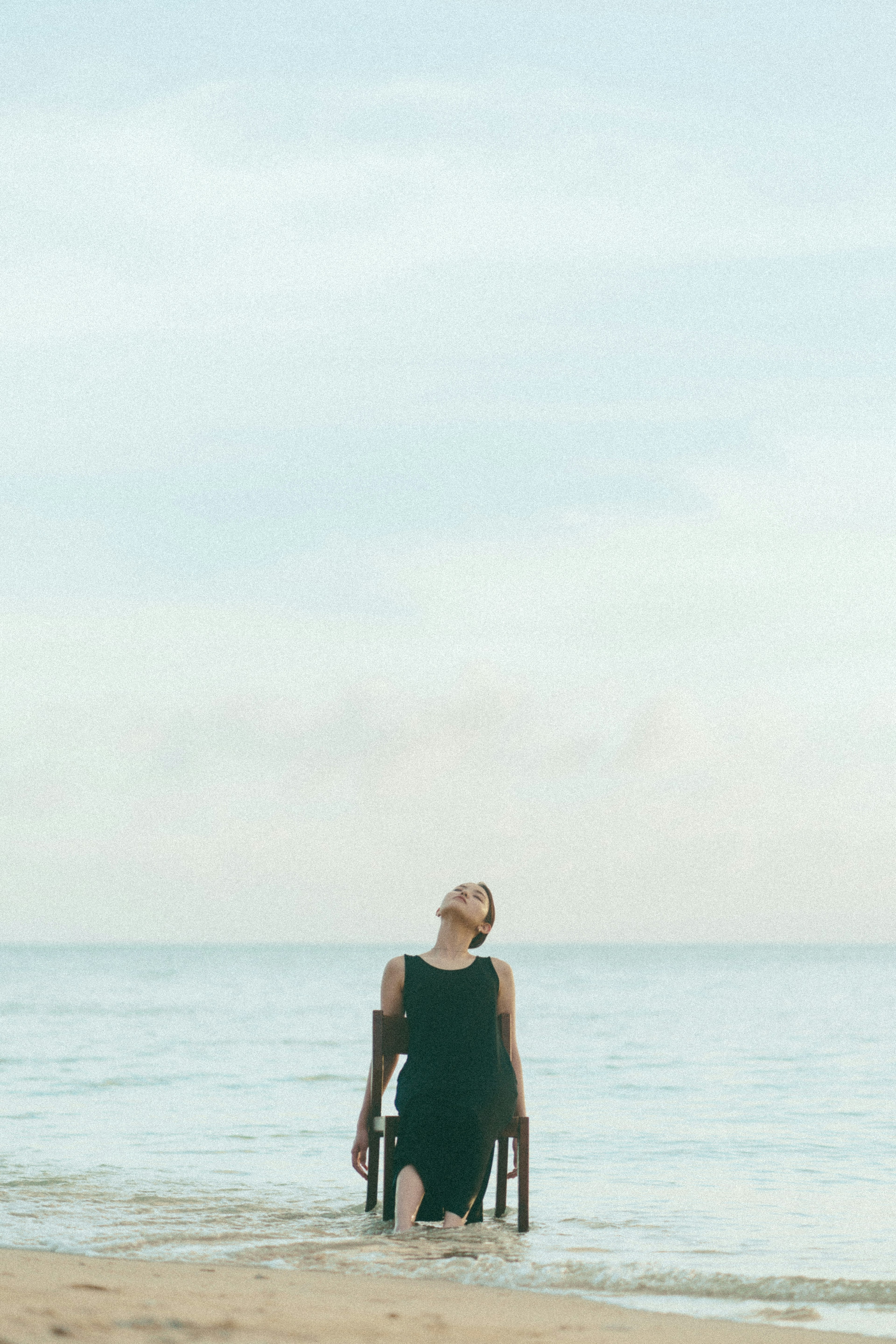 Silhouette einer Frau, die einen Stuhl am Strand hält