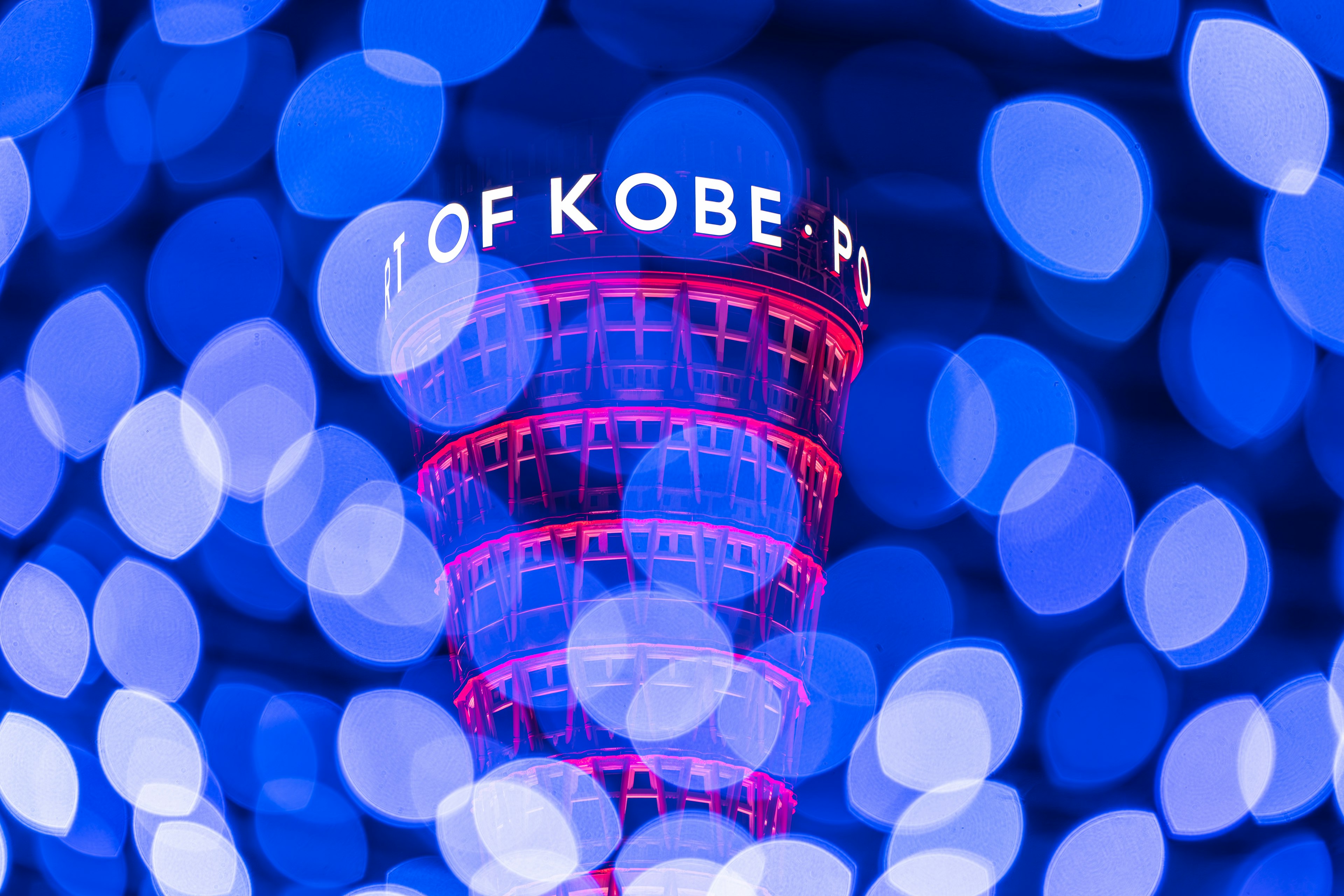 Tháp cảng Kobe được chiếu sáng vào ban đêm với hiệu ứng bokeh đầy màu sắc trên nền xanh lam