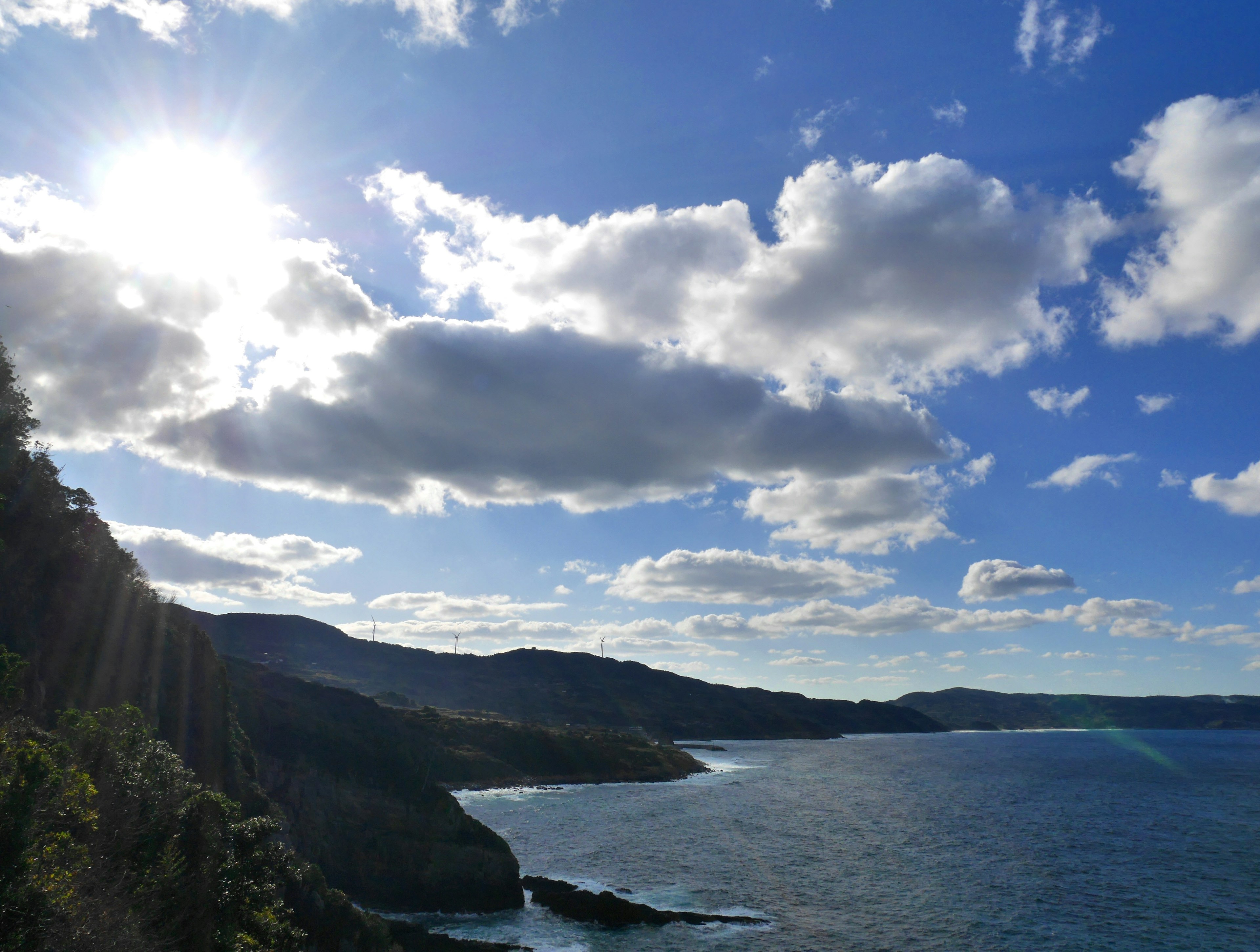 青い海と白い雲のある風景に太陽が輝く