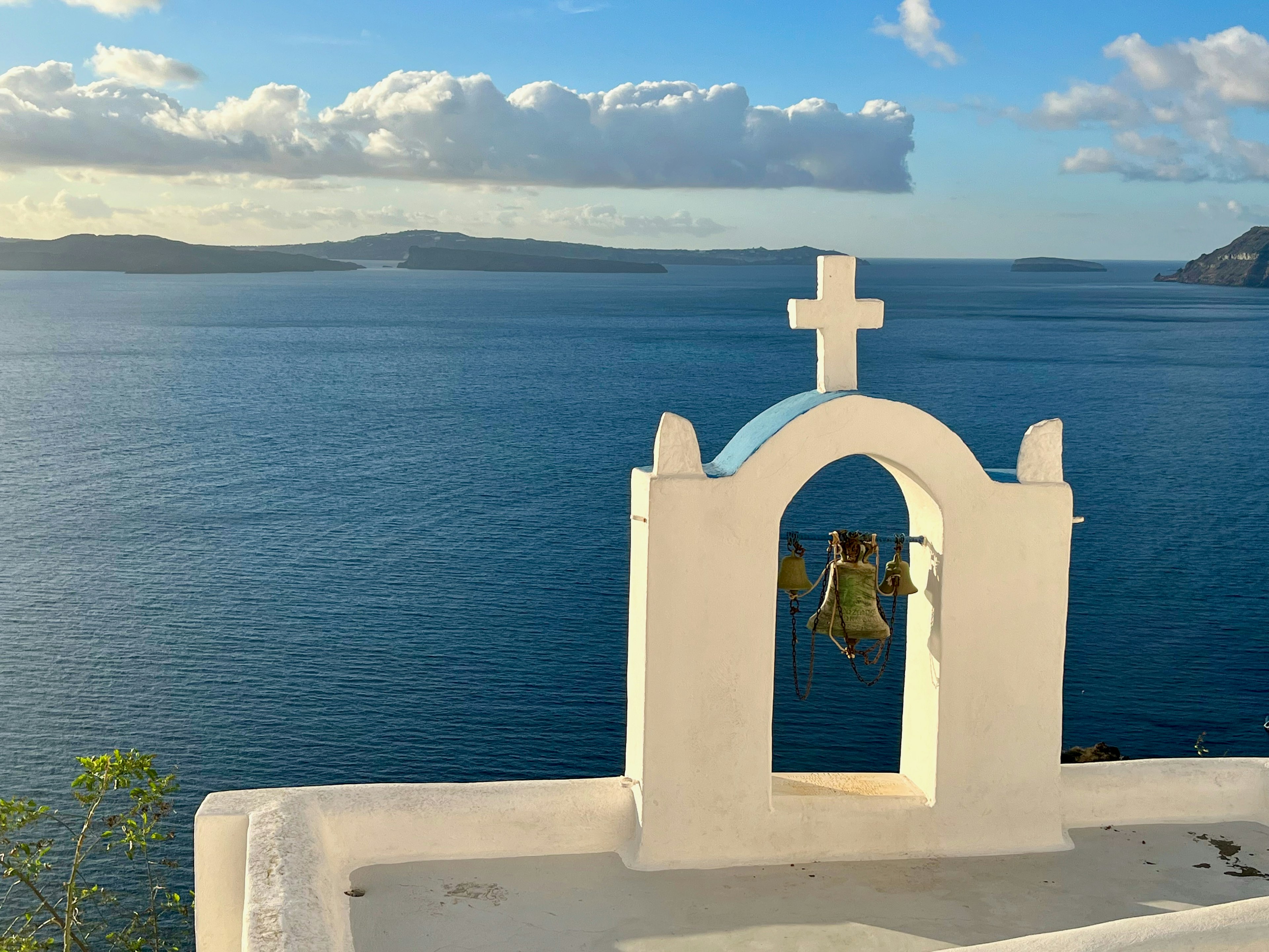 White church bell tower with a blue sea and clouds in the background