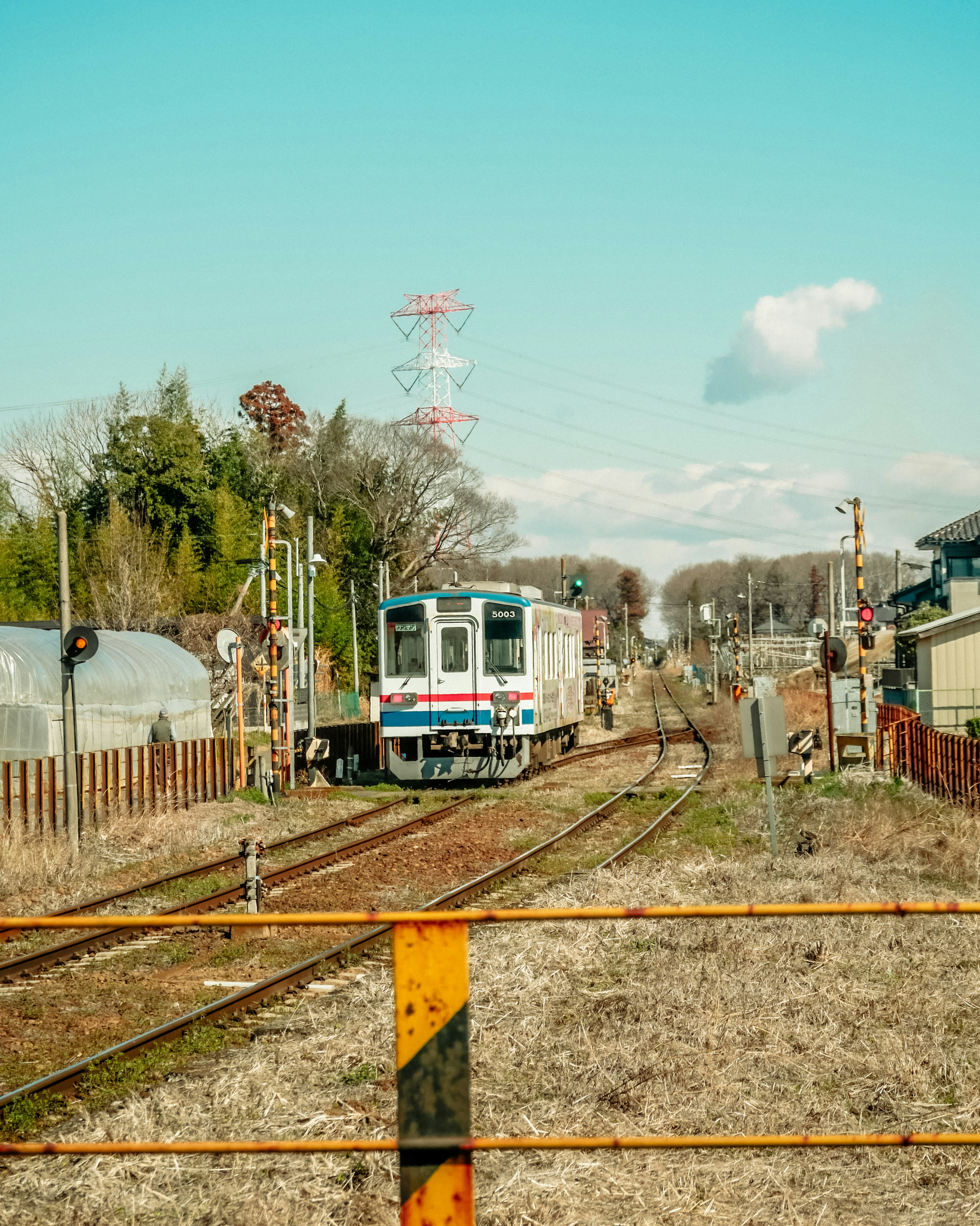 Train approaching on tracks with clear blue sky and surrounding landscape