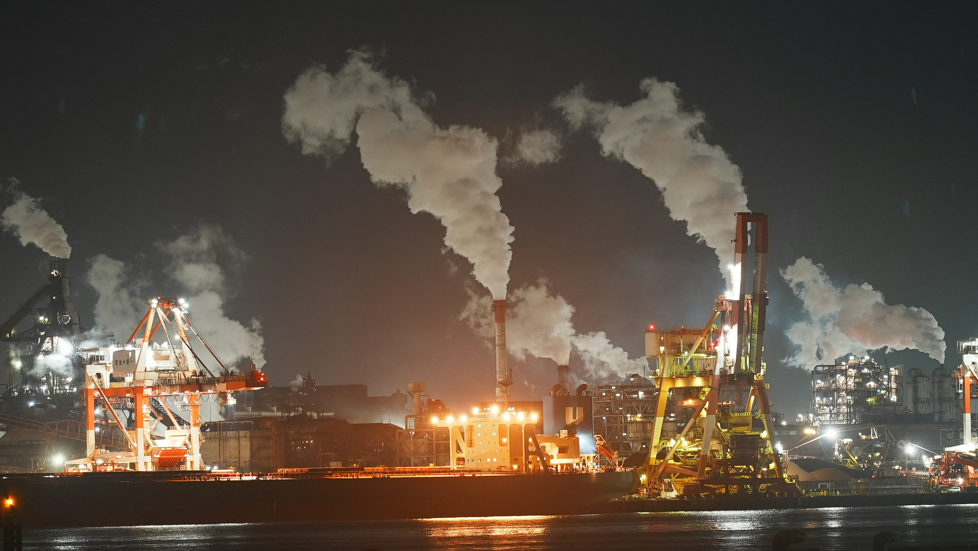 Zona industrial nocturna con humo y luces