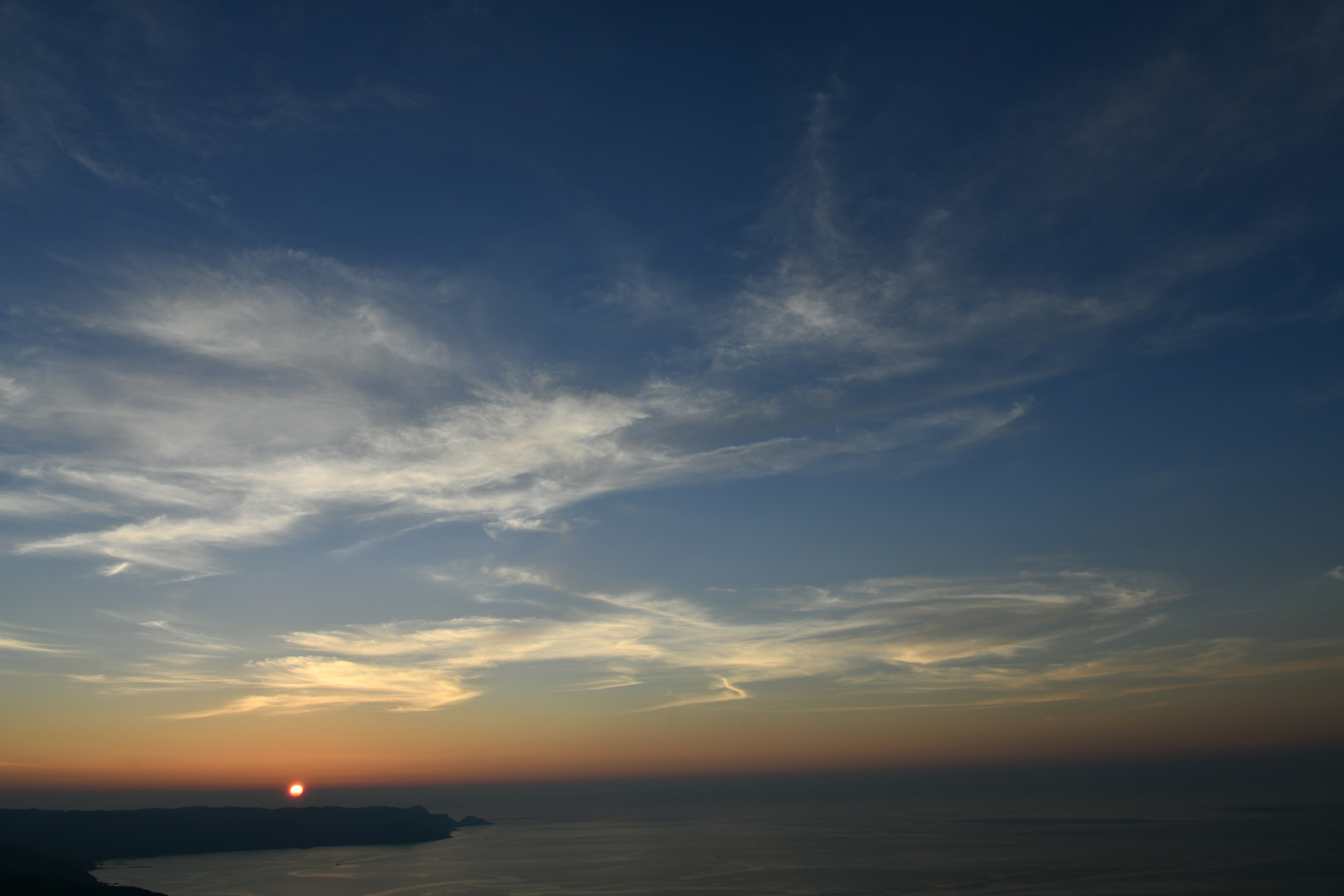 Sonnenuntergang über dem Ozean mit blauem Himmel und Wolken