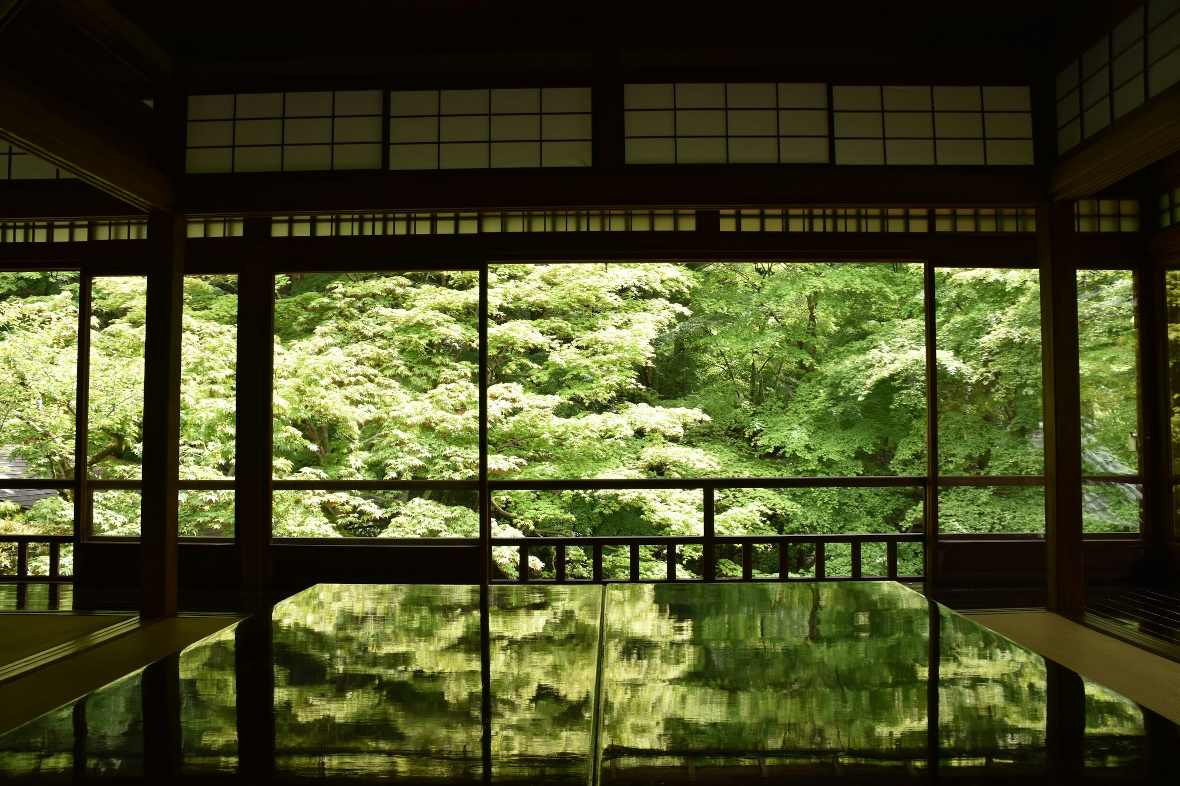 Blick von innen auf ein traditionelles japanisches Gebäude, umgeben von üppigem Grün