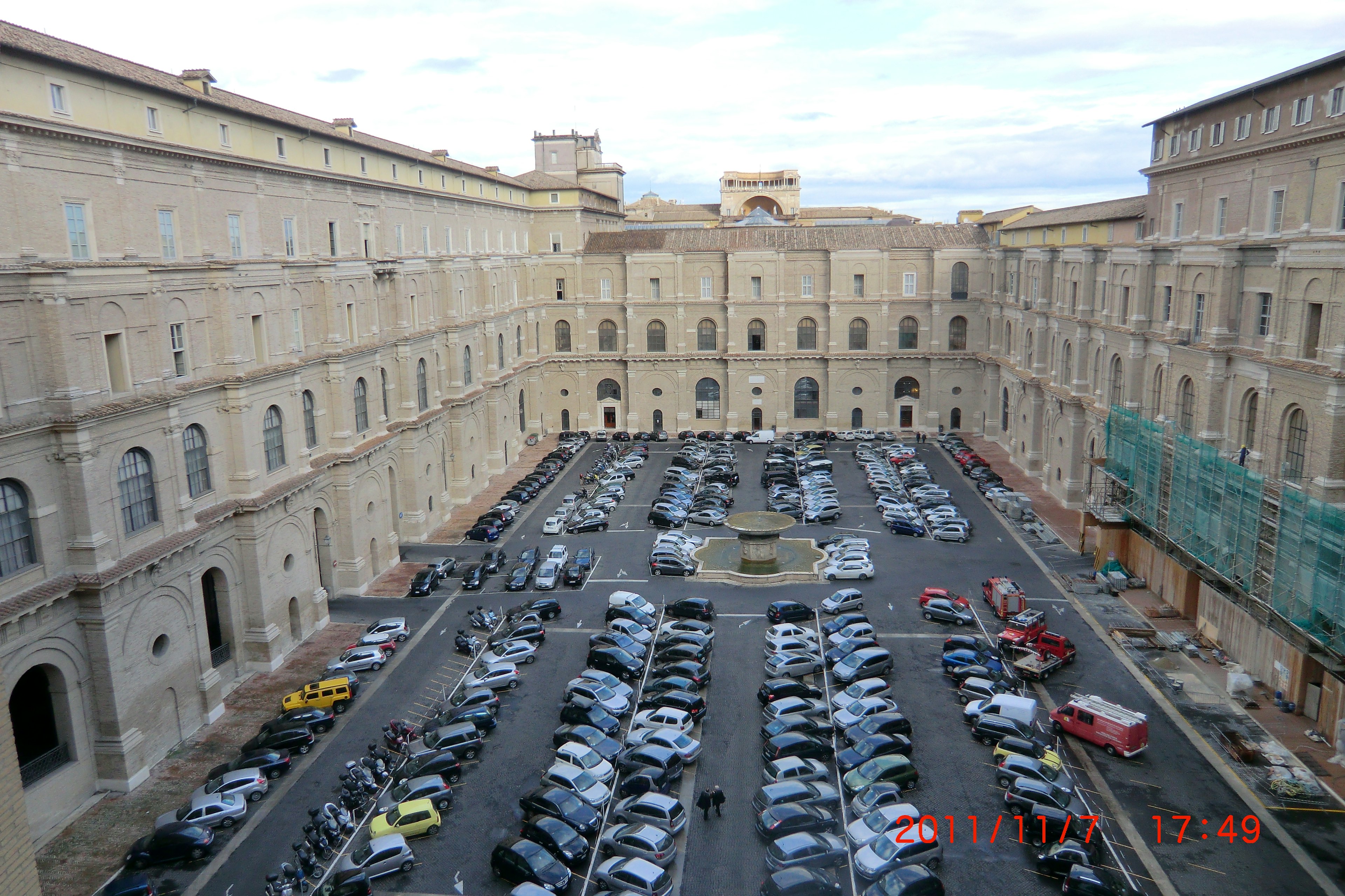 Piazza della Città del Vaticano con numerose auto parcheggiate e edifici storici