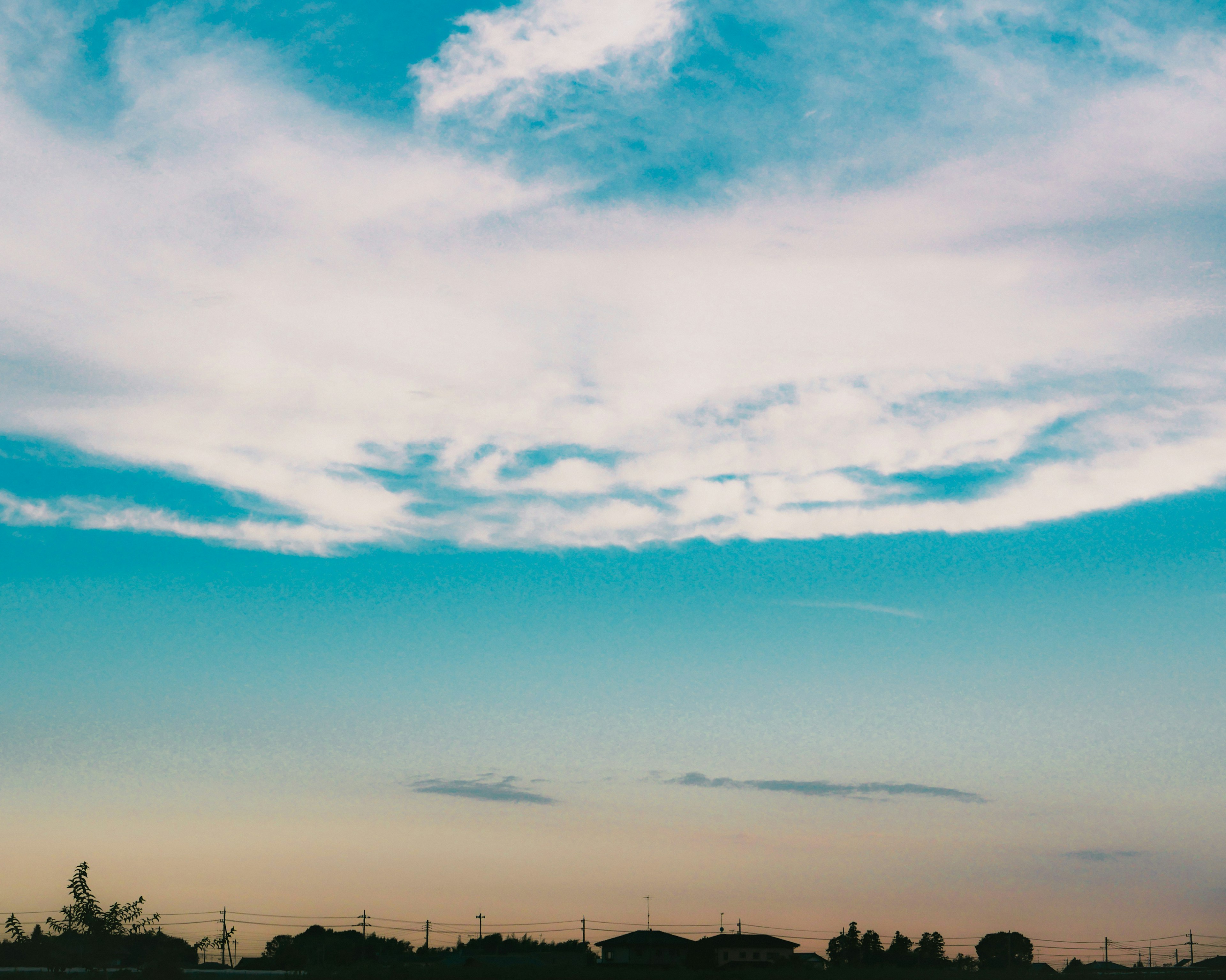 Une vue panoramique du ciel bleu avec des nuages blancs duveteux au coucher du soleil