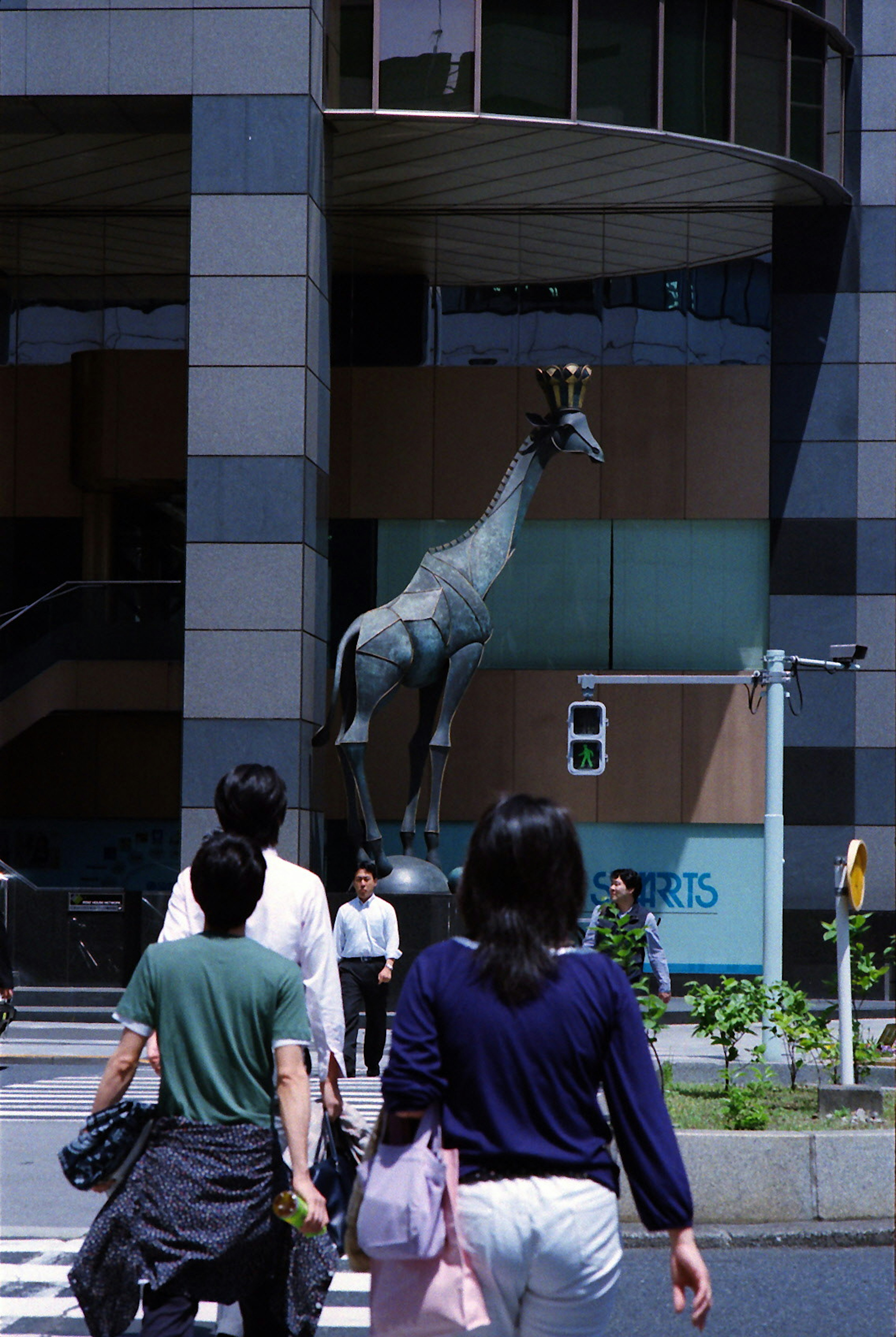 Menschen, die auf der Straße gehen, mit einer gekrönten Giraffenskulptur im Blick