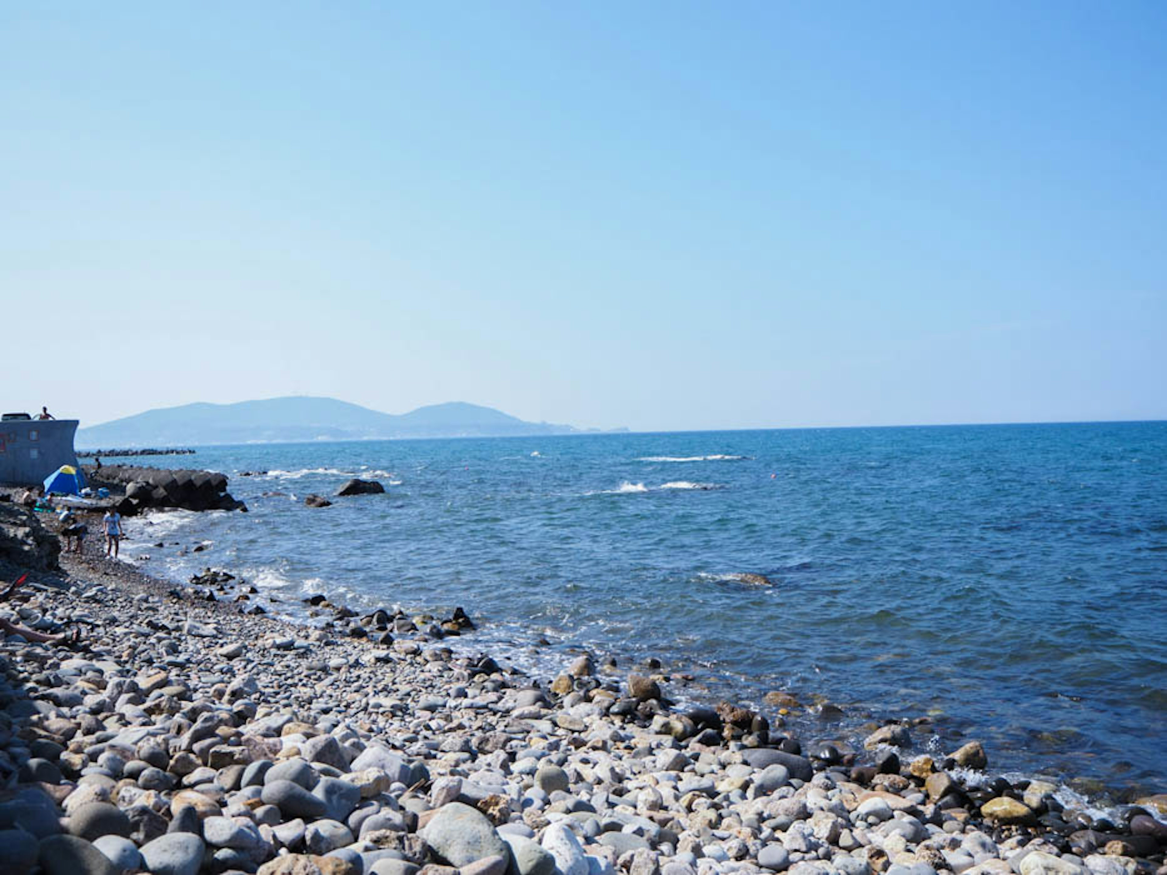 Vista panoramica di una spiaggia ghiaiosa con acqua blu chiara