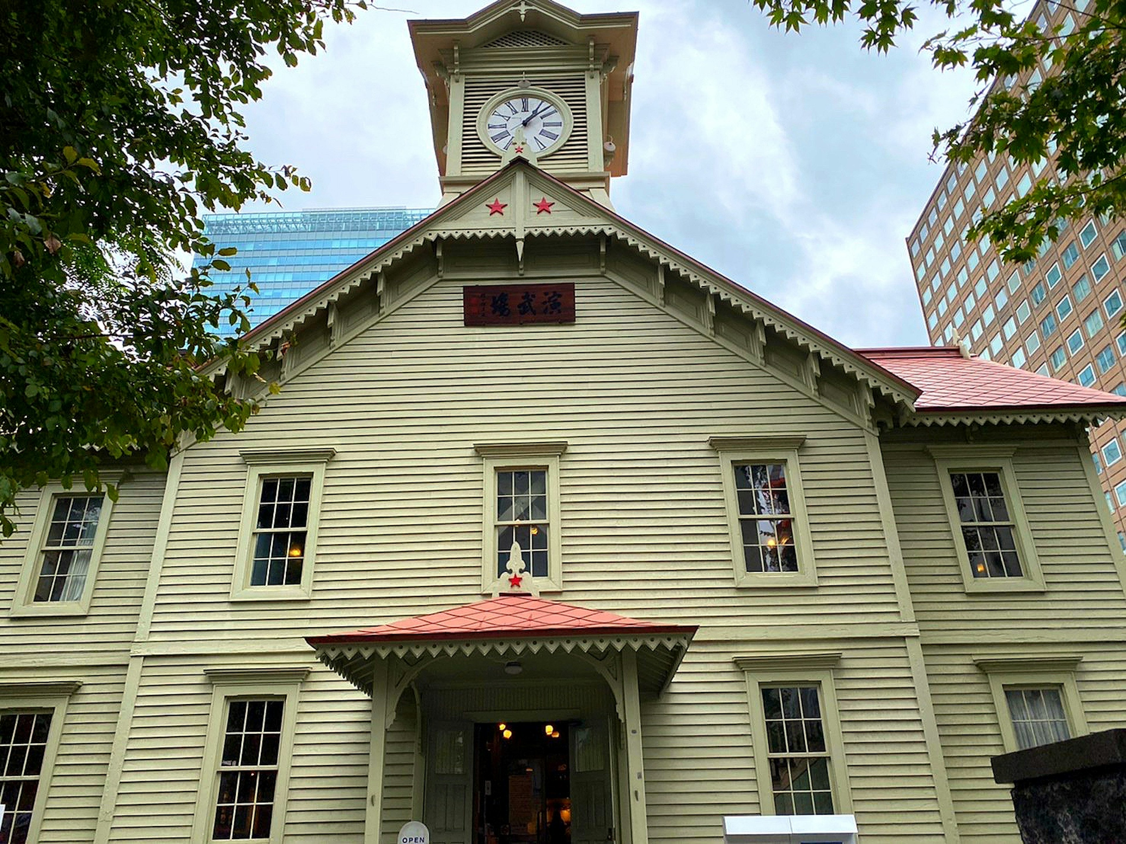 Green wooden building with a prominent clock tower