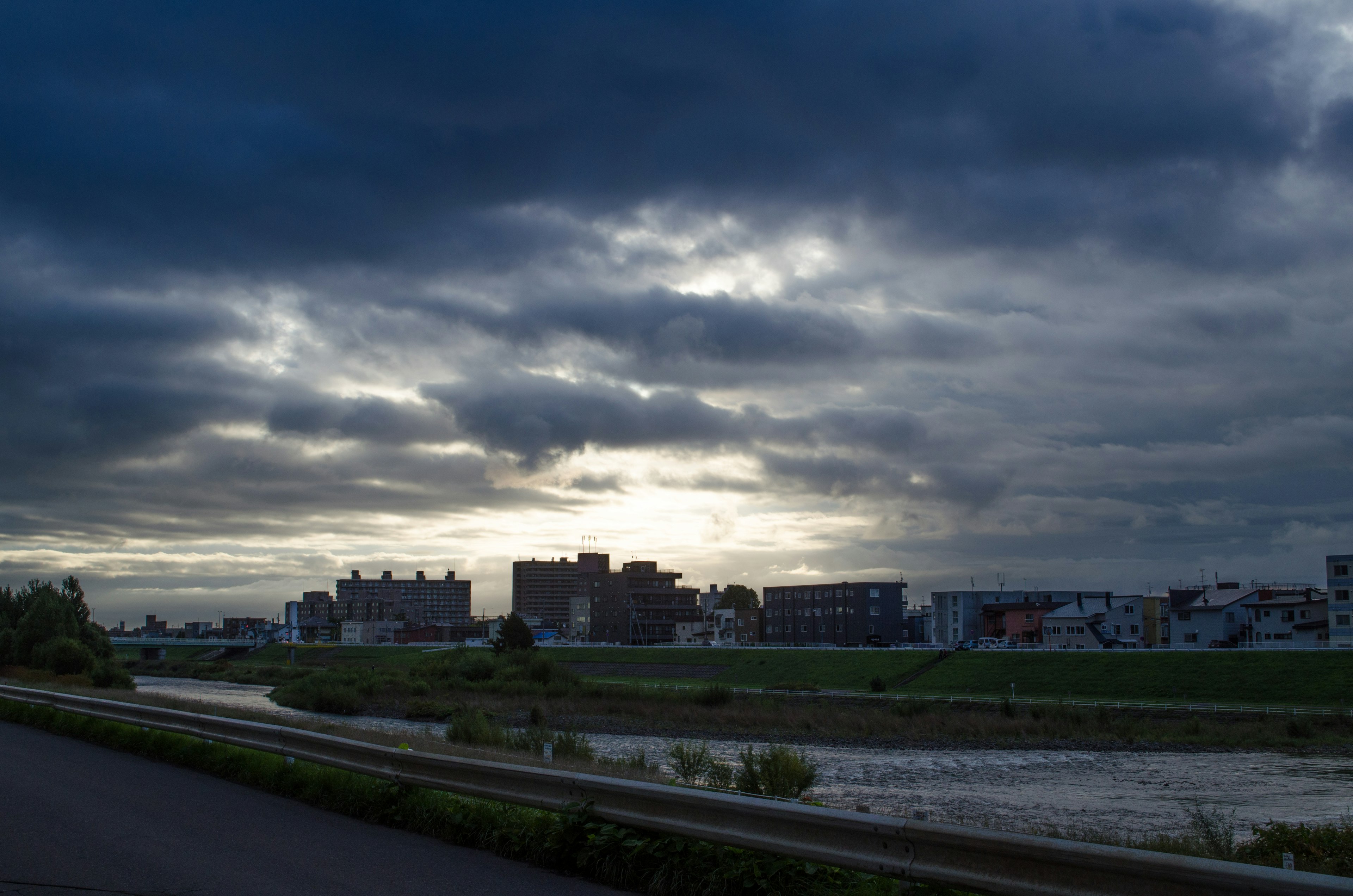 Nubes oscuras sobre un paisaje fluvial con edificios visibles