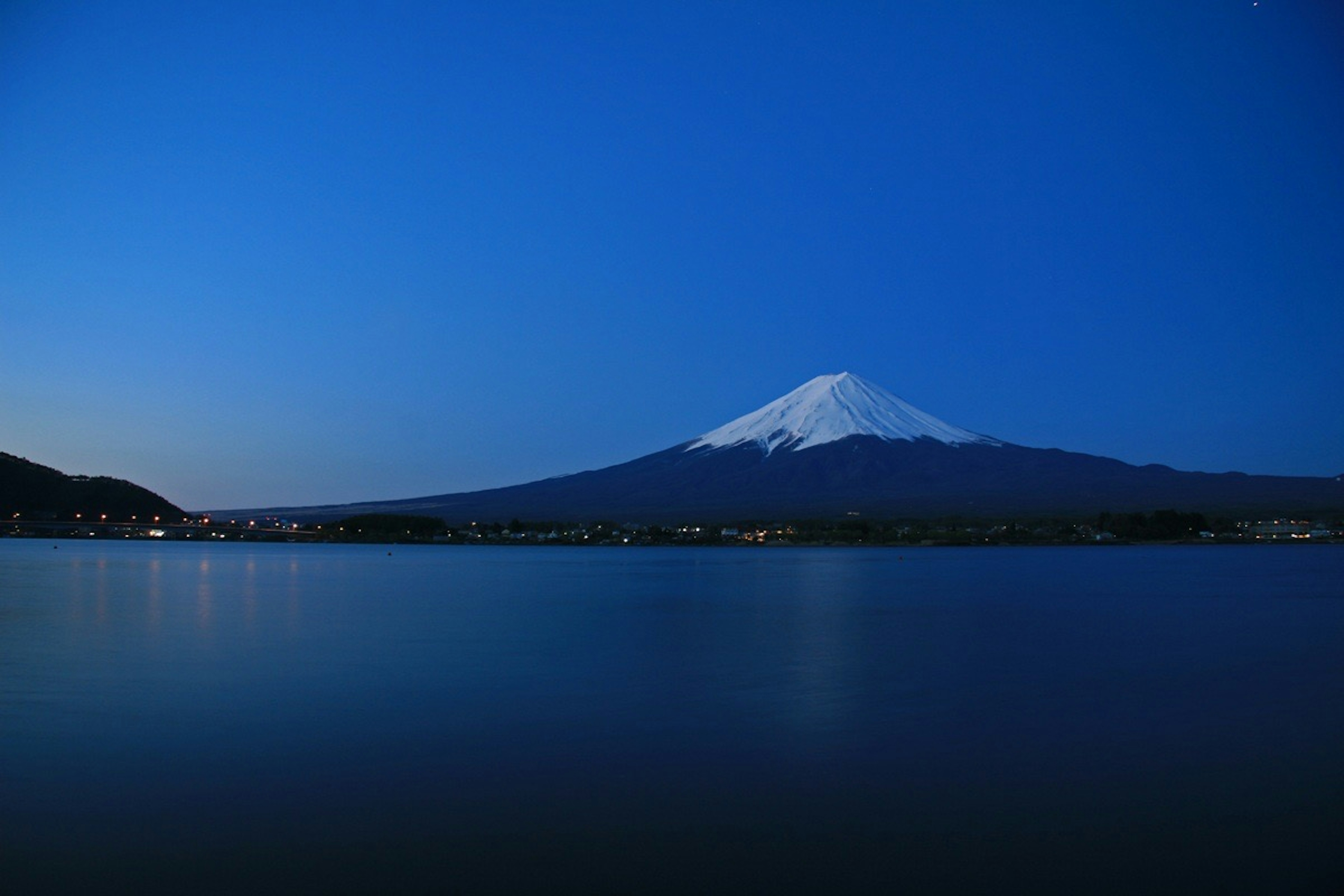 富士山が青い夜空の下で湖に映る美しい風景