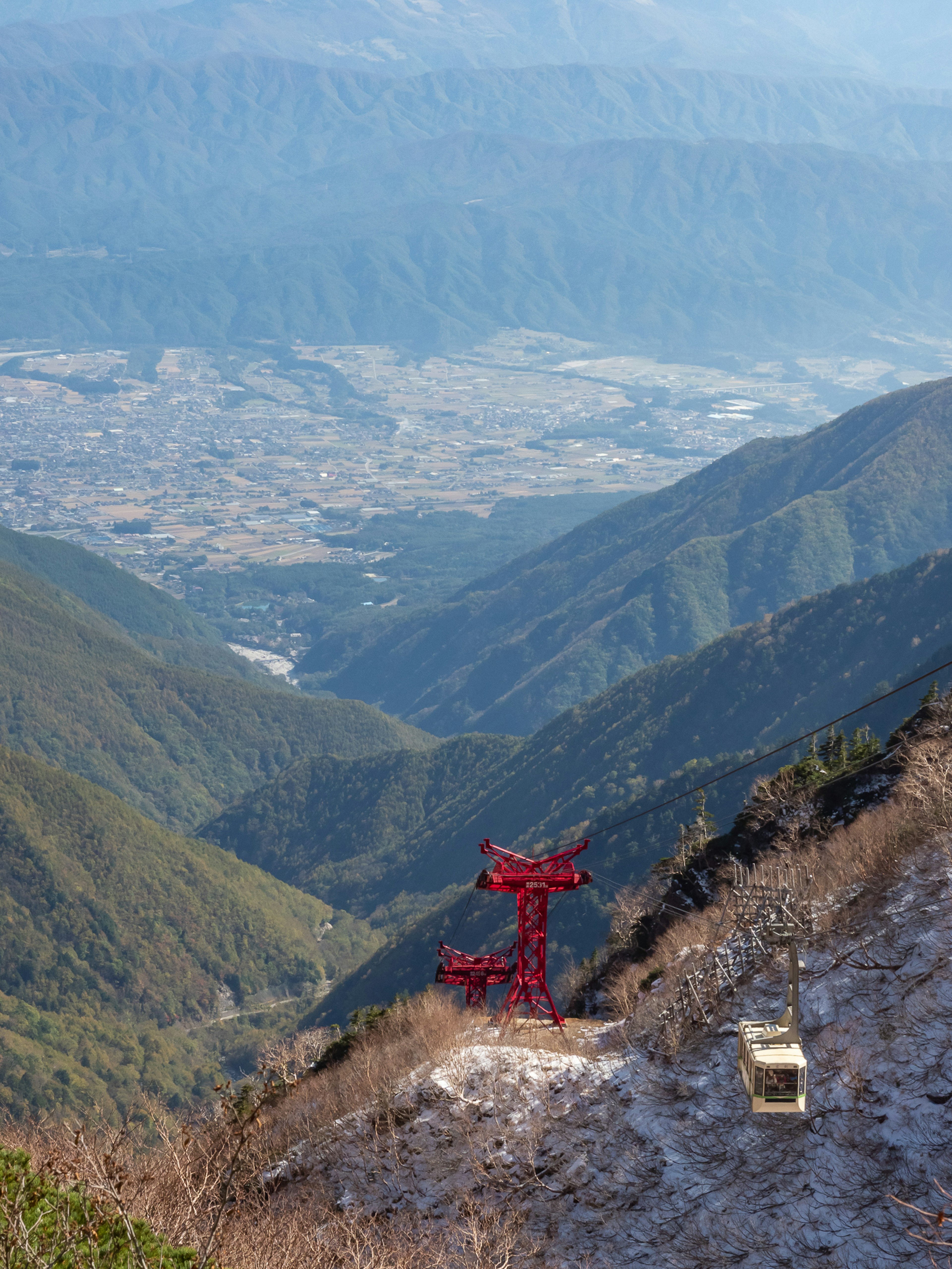 Vista panoramica delle montagne con una funivia rossa e una valle sottostante