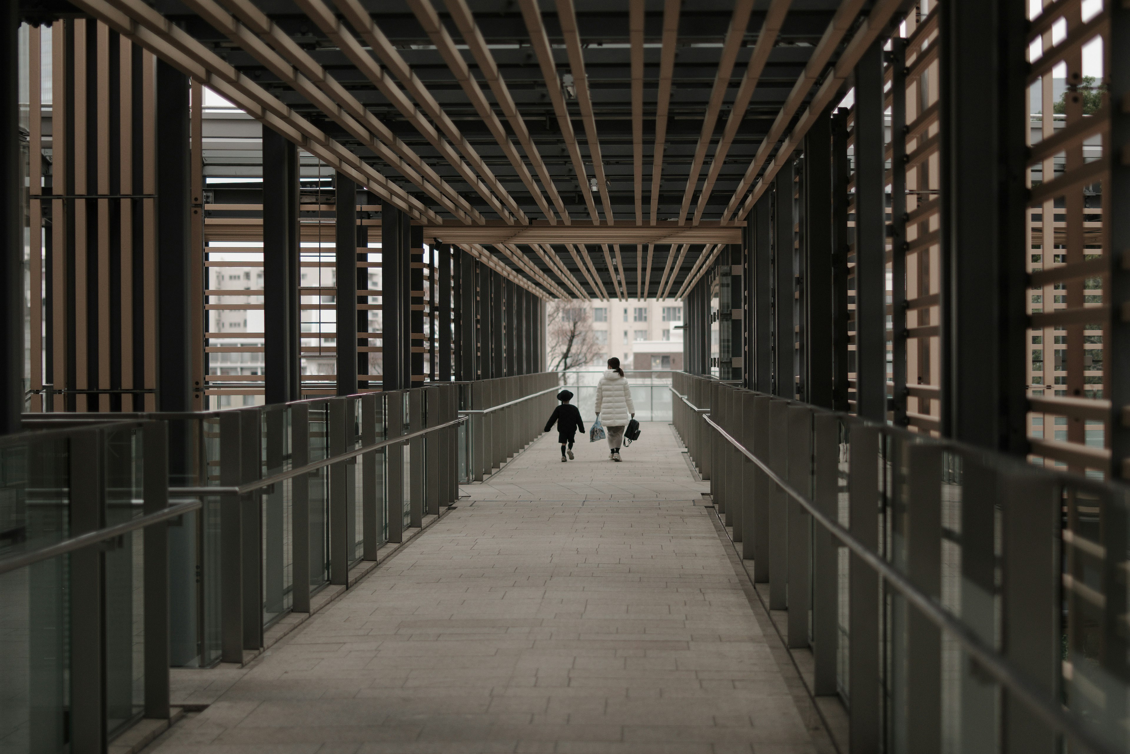 Pasarela moderna con vigas de madera y un padre caminando con niños