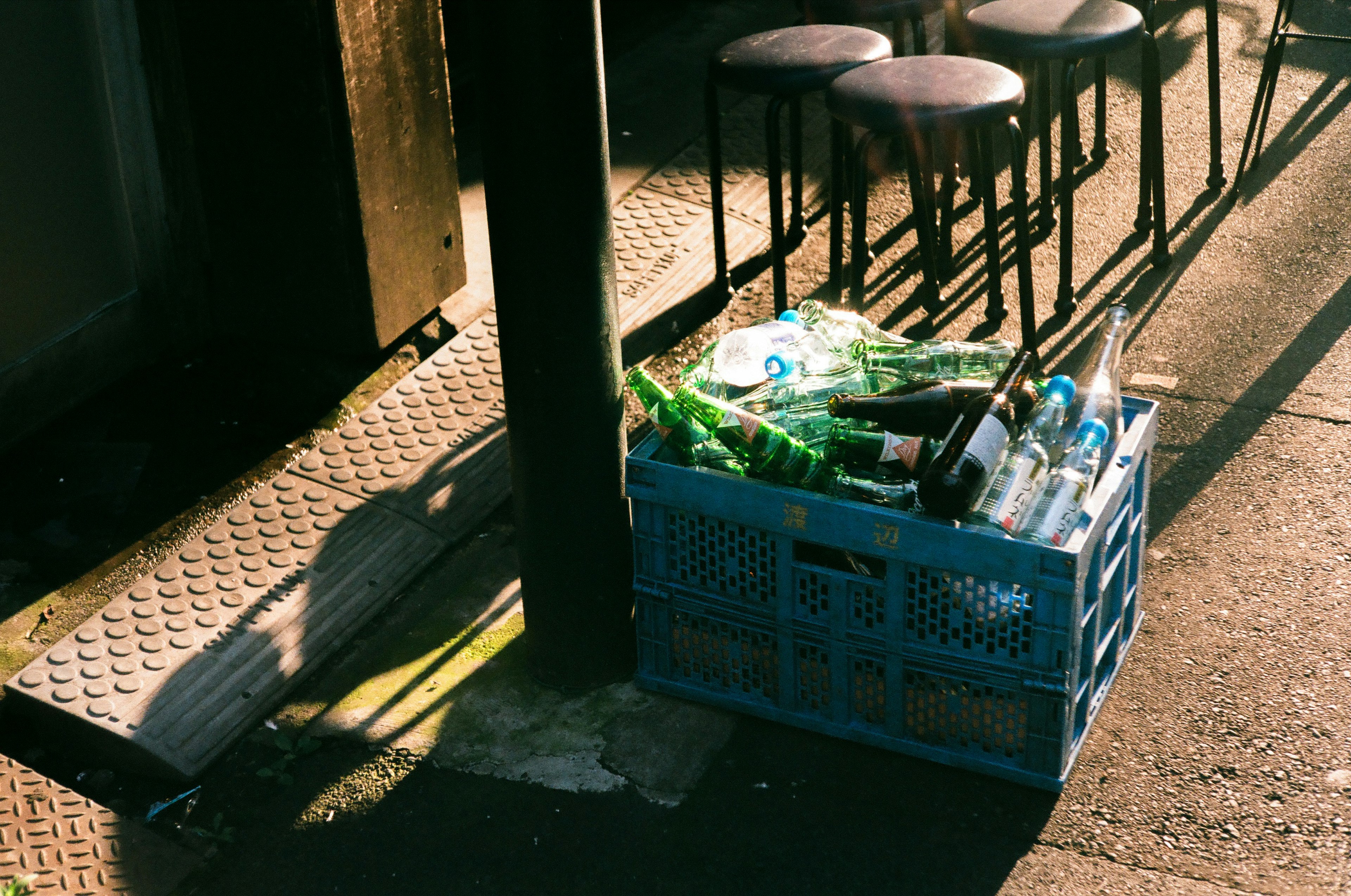 Eine blaue Kunststoffkiste voller leerer Flaschen und recycelbarer Abfälle