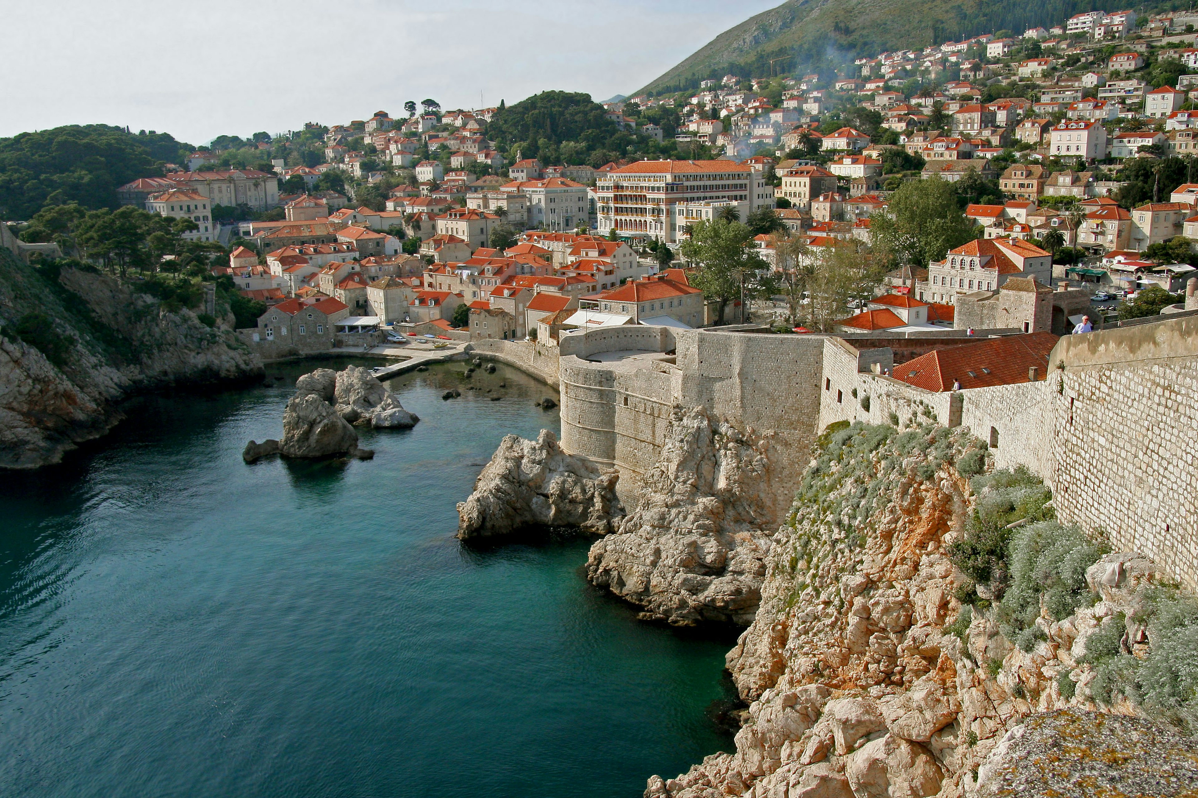 Murailles anciennes le long d'une mer sereine avec des maisons à toits orange