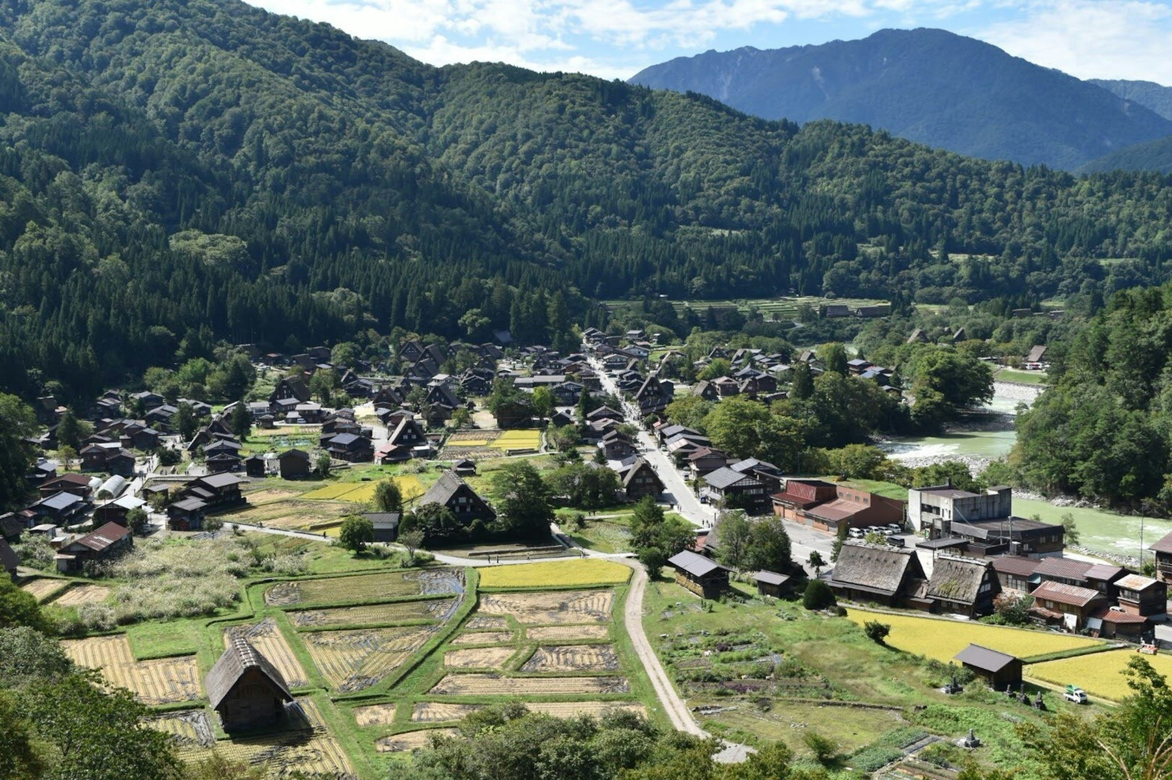 Vista panoramica di un villaggio tradizionale circondato da montagne con campi di riso