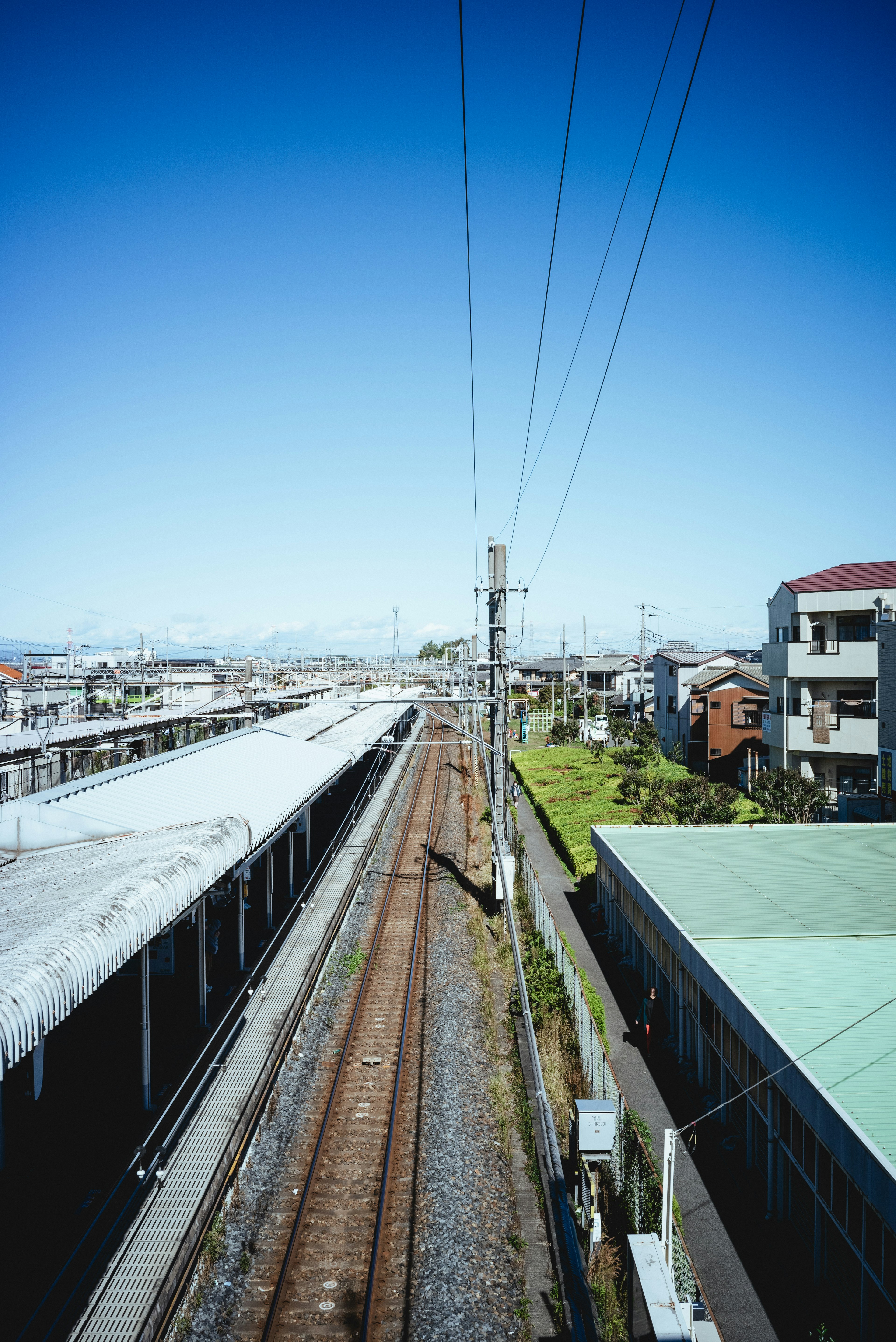 ทัศนียภาพสถานีรถไฟที่มีรางรถไฟและอาคารใต้ท้องฟ้าสีฟ้า