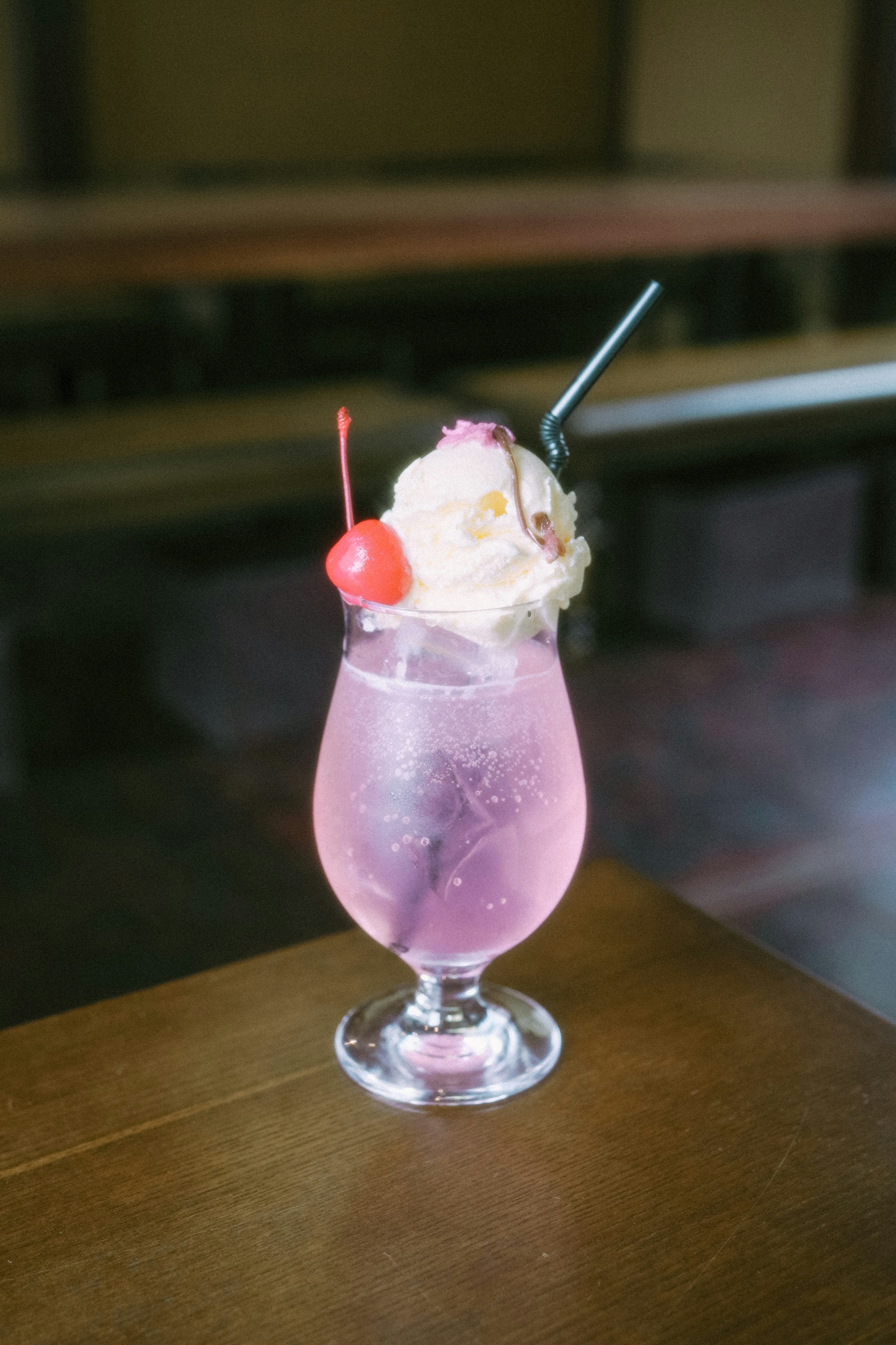 A beautiful pink cocktail topped with cream and a cherry